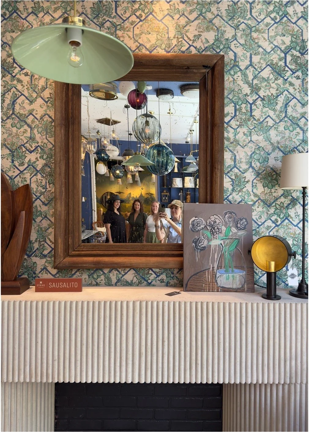 Framed mirror and fluted cabinet against patterned wallpaper