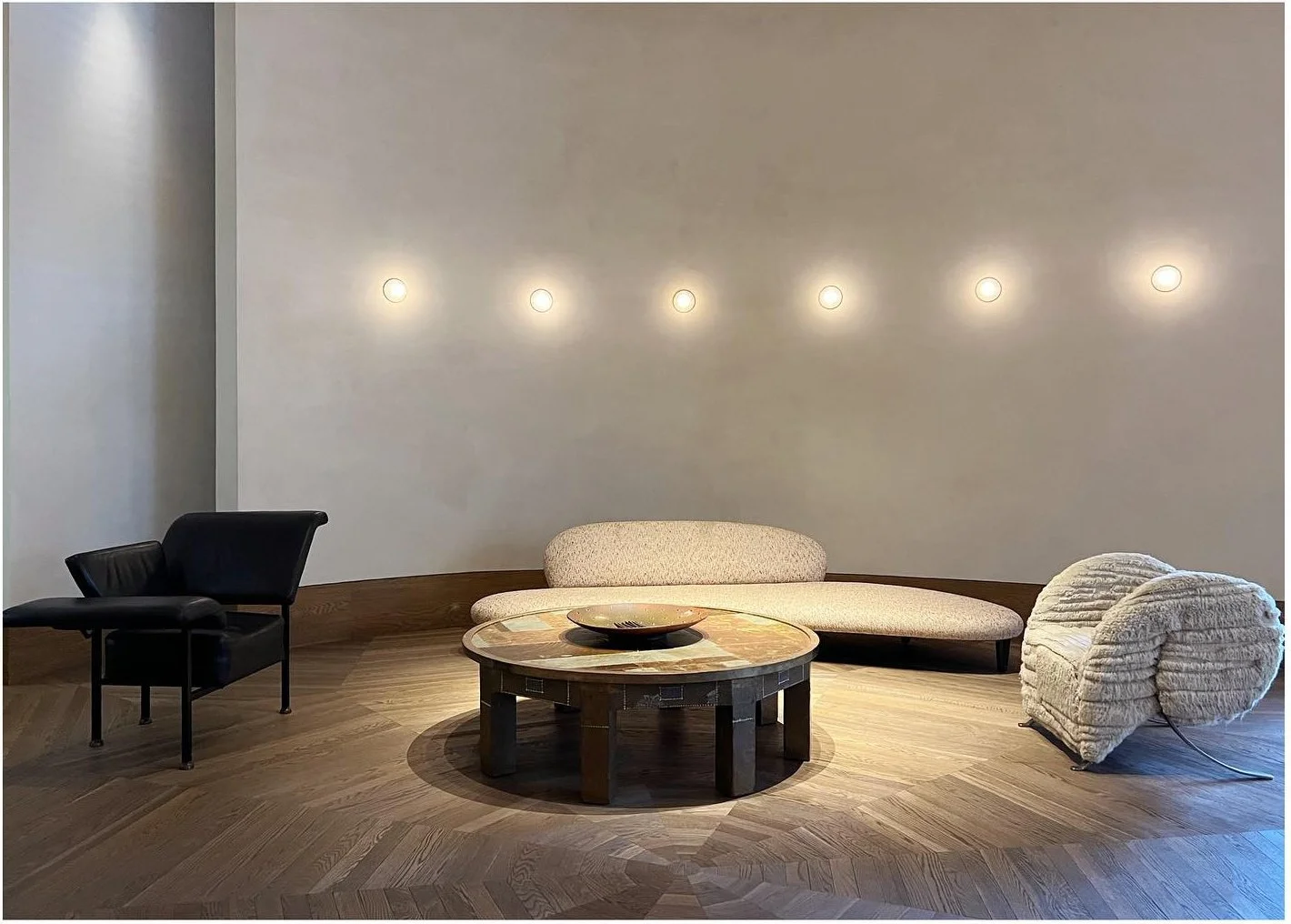 Low sculptural seating and tables against a softly illuminated curved wall