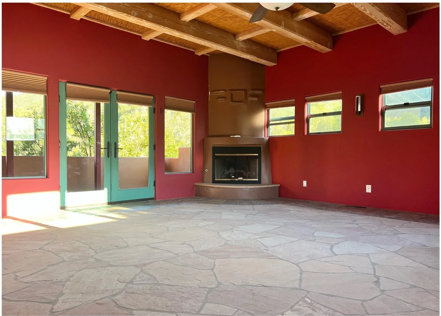Original red-walled living room with stone flooring large windows and exposed beams