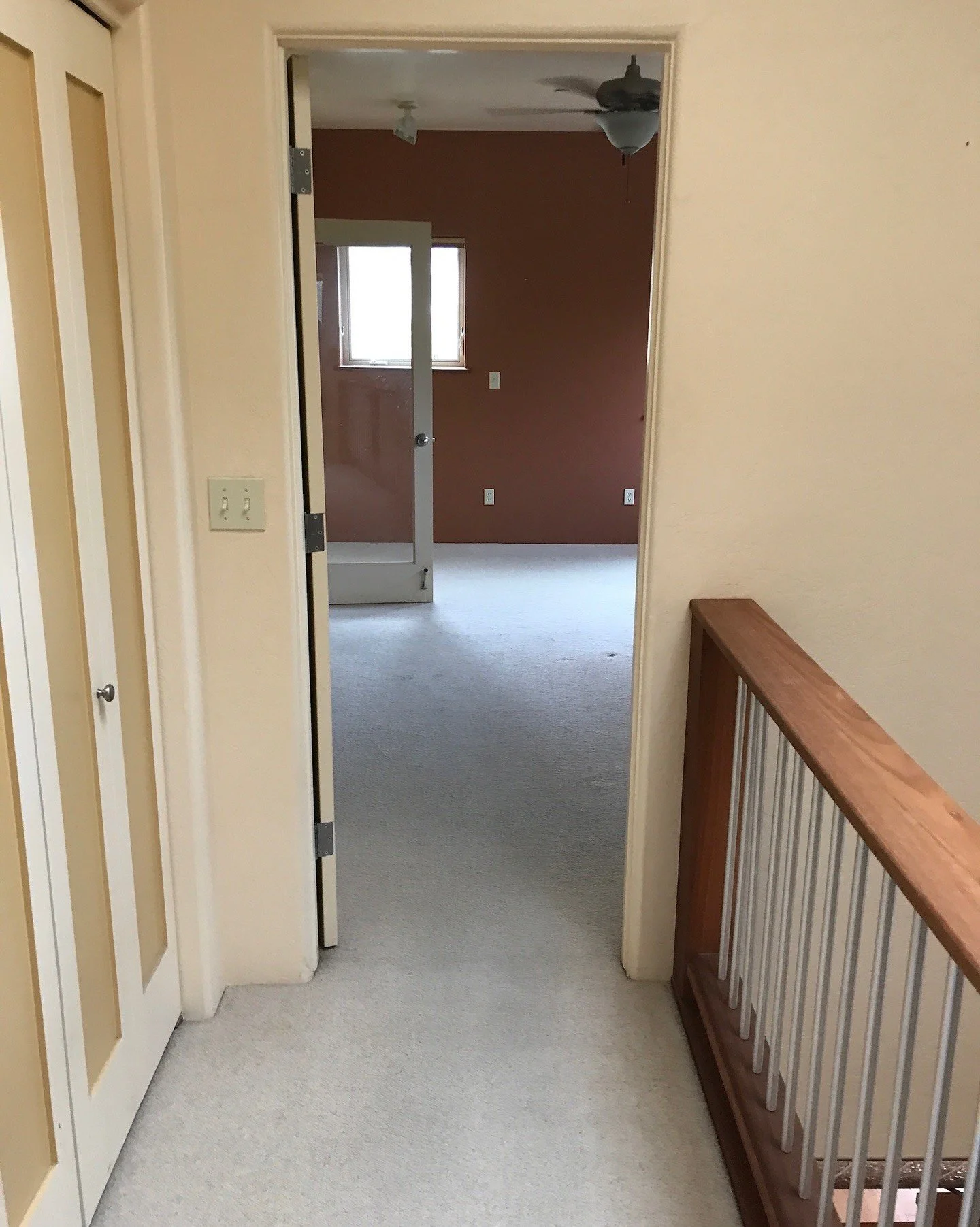 Before renovation: carpeted hallway with wood stair rails