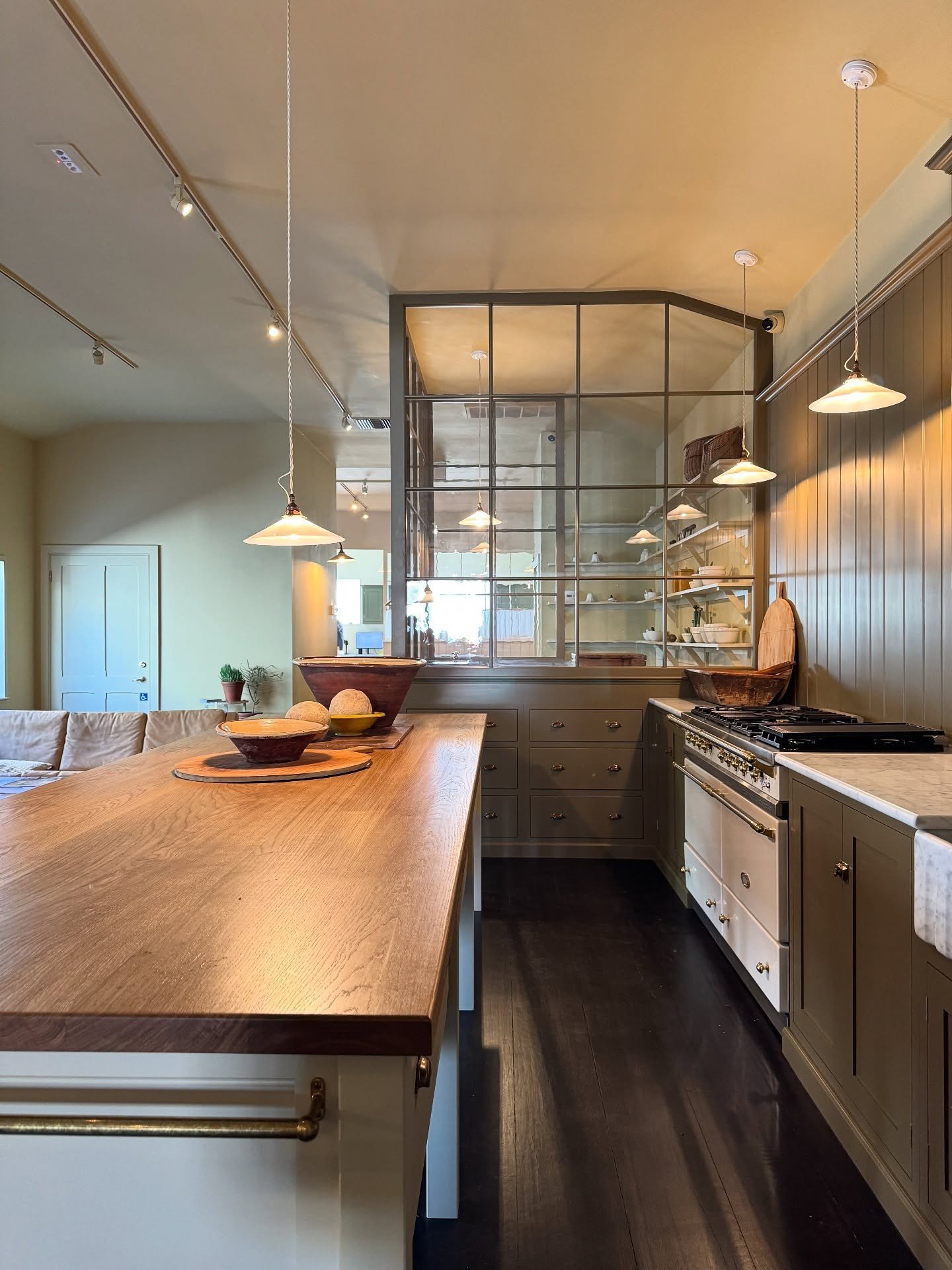 Long wood kitchen island beside a black-framed glazed partition