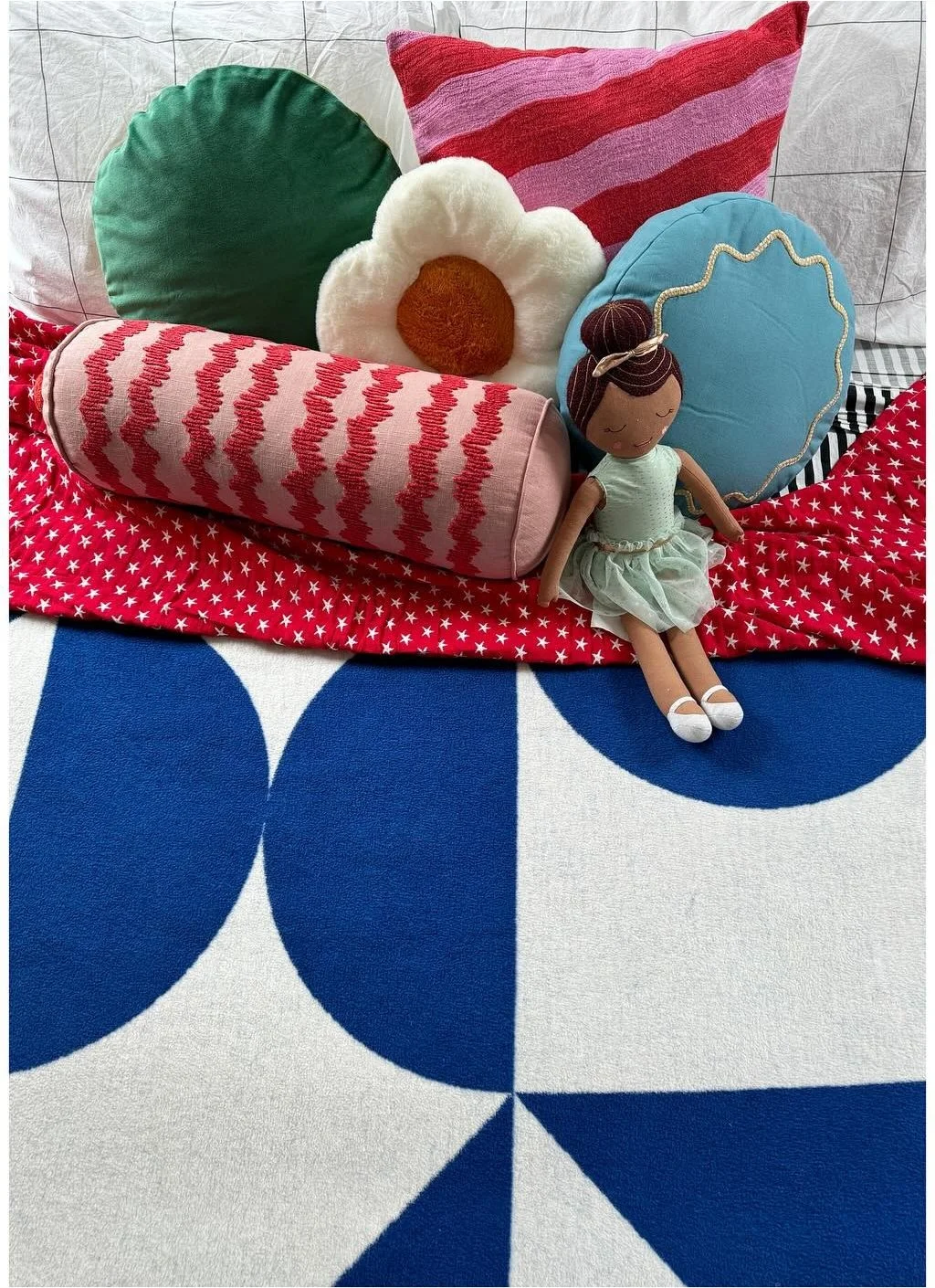 Colorful sculptural pillows on a red and blue patterned seat