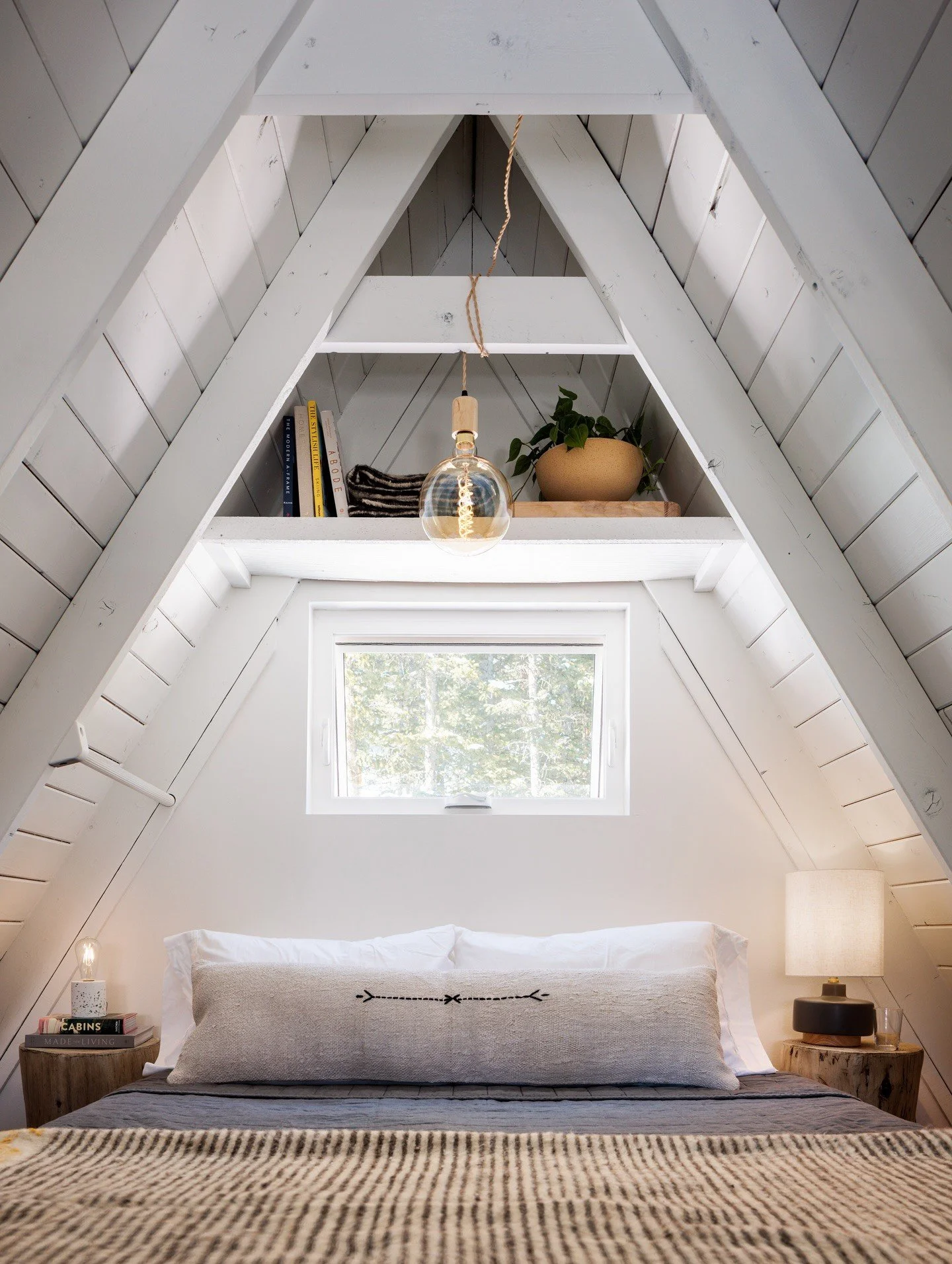 White A-frame bedroom with triangular beams and layered bedding