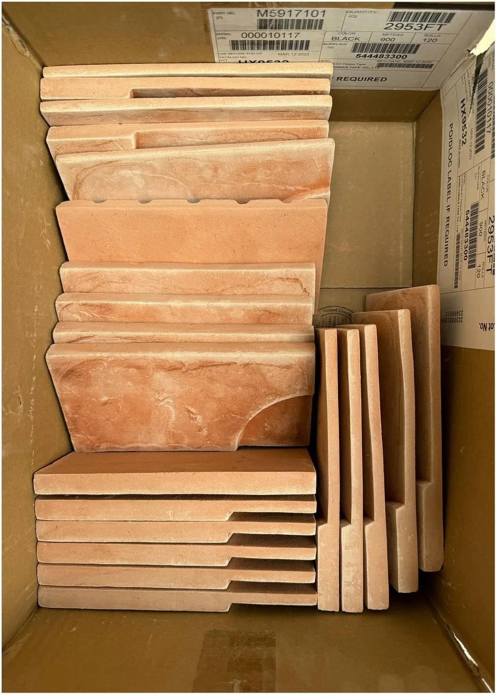 Stacked terracotta tile samples in a cardboard display box