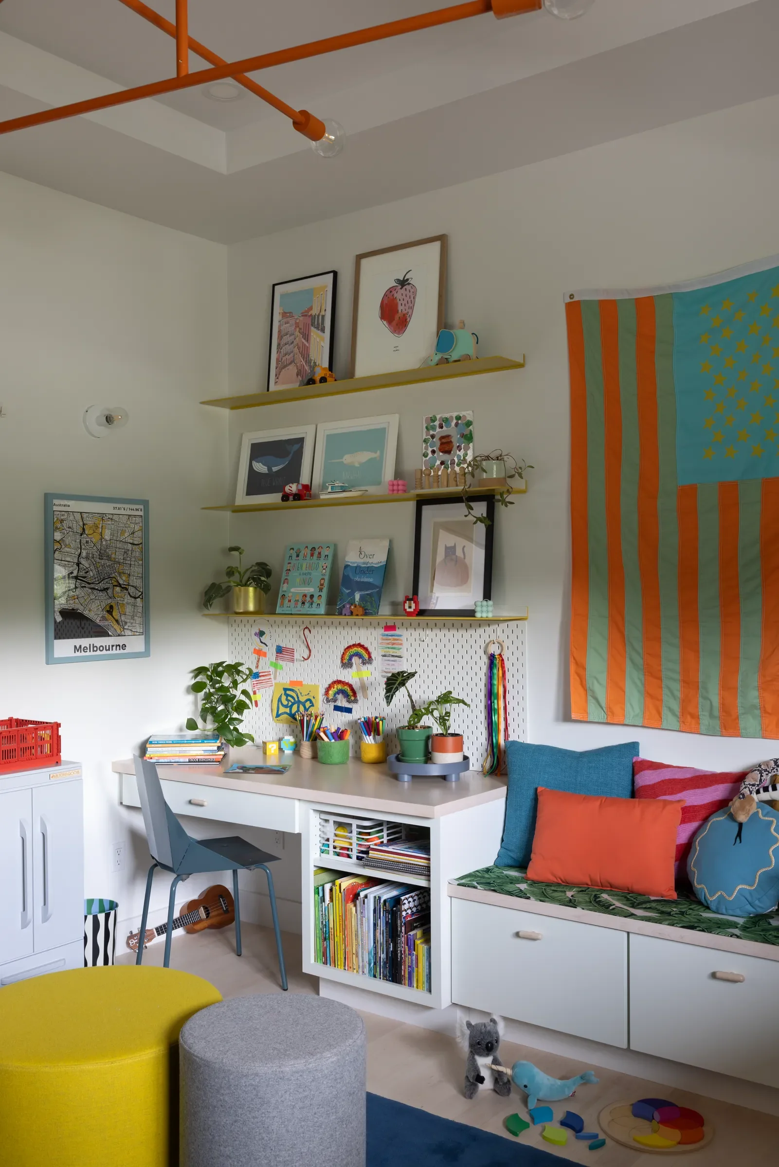 Children’s playroom with a desk, bright cushions, and shelves of art and toys.