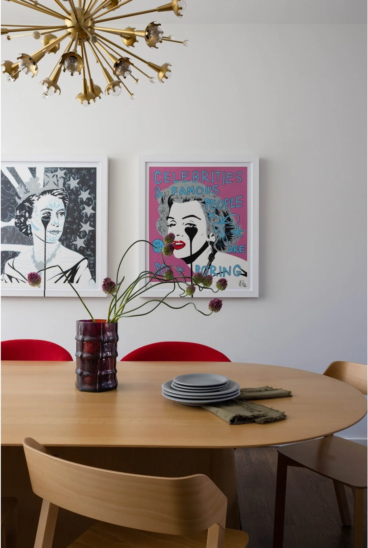 Round dining table beneath brass lighting and framed portraits