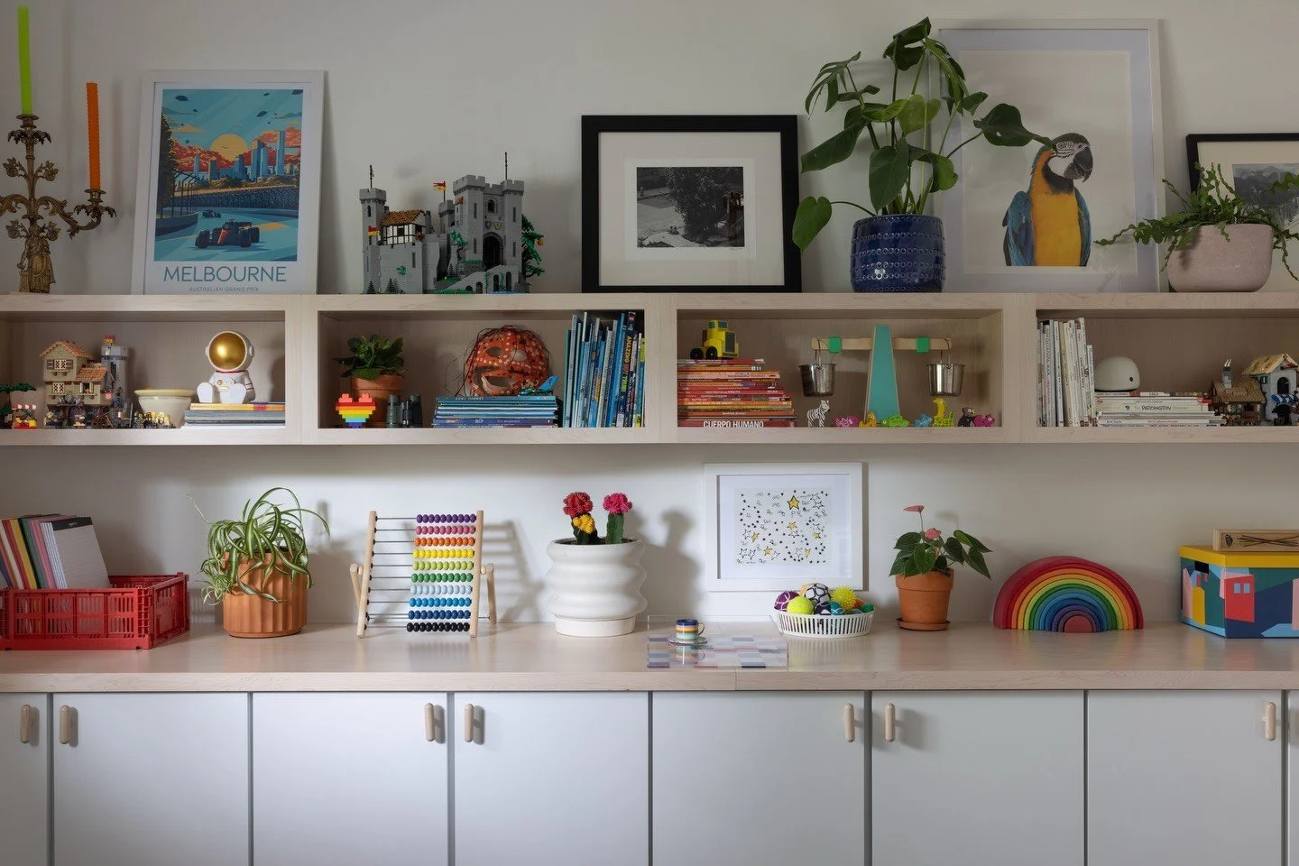 White storage cabinets and open shelves styled with art and toys