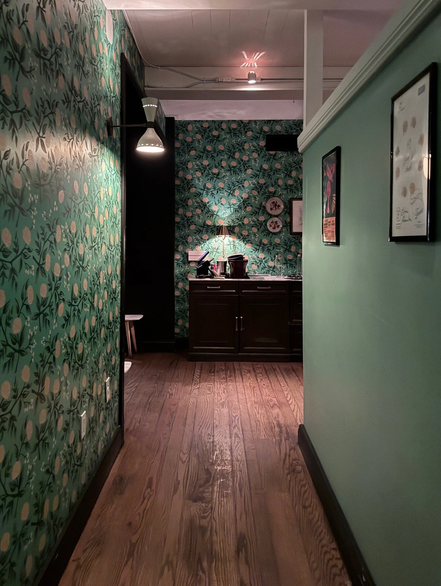 Green hallway with floral wallpaper and a wood floor