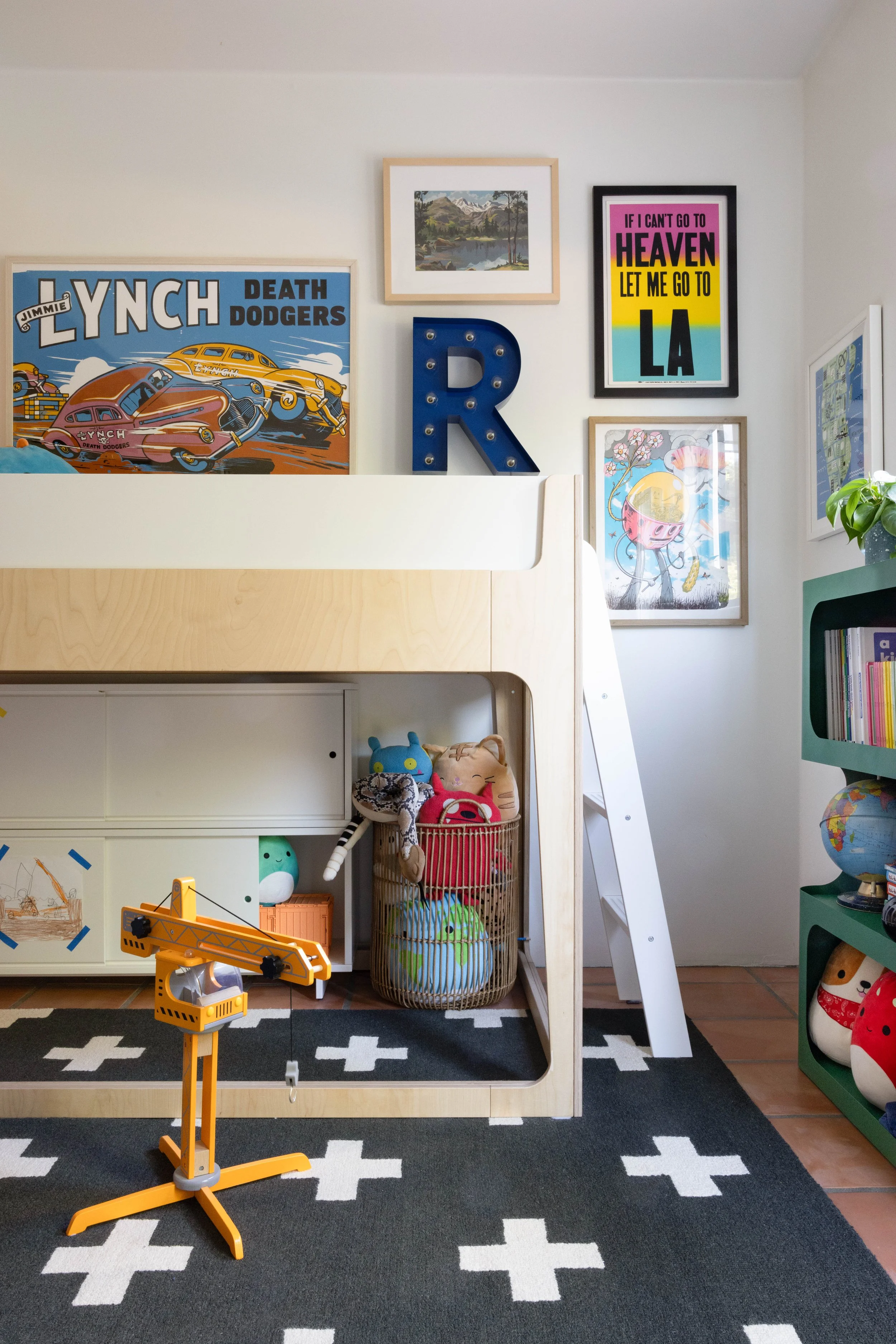 Child’s room with a loft bed, framed posters, and a black-and-white rug.