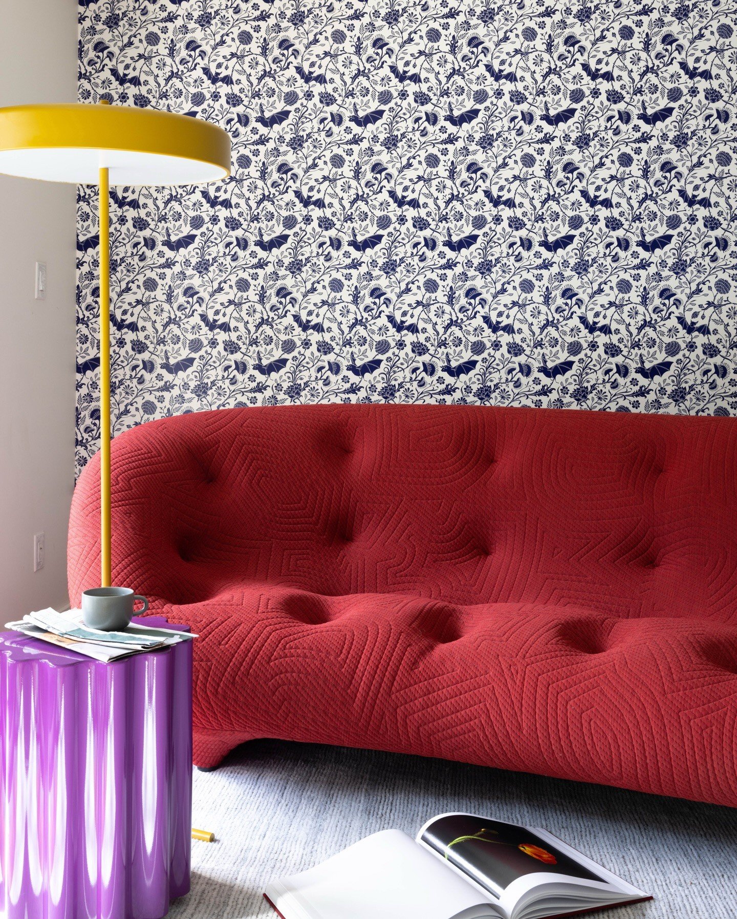 Red tufted sofa beside a purple fluted table and yellow lamp