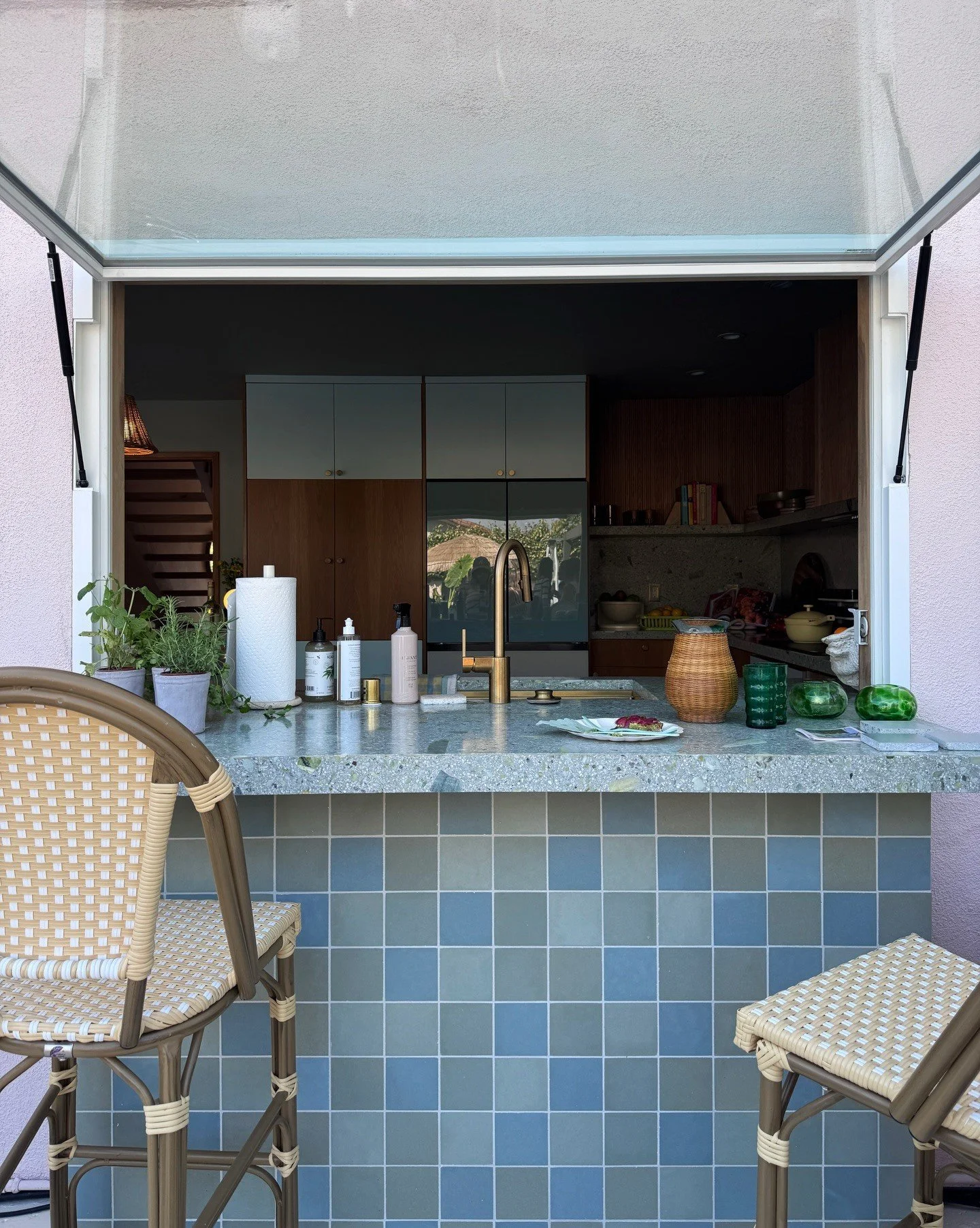 Open serving hatch with blue tile and woven bar stools