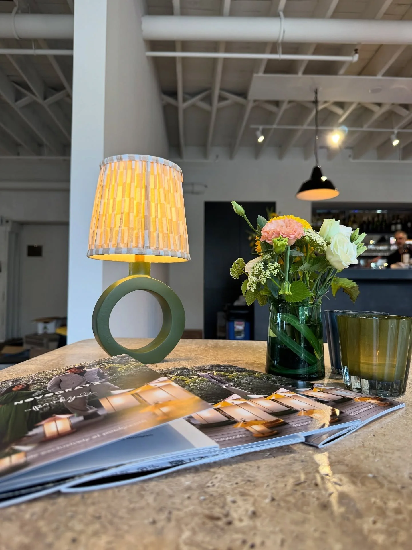 Circular-base table lamp with yellow pleated shade and flowers