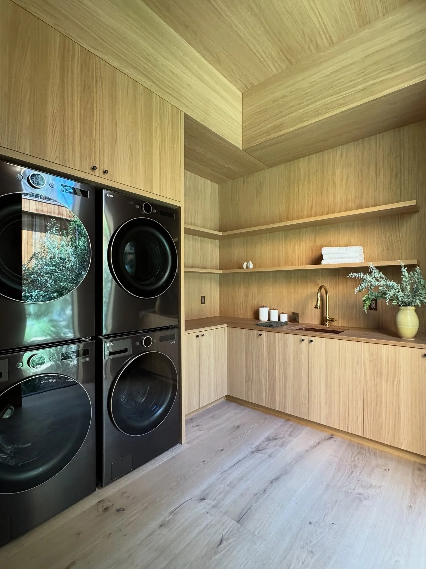 Wood-paneled laundry room with stacked black appliances