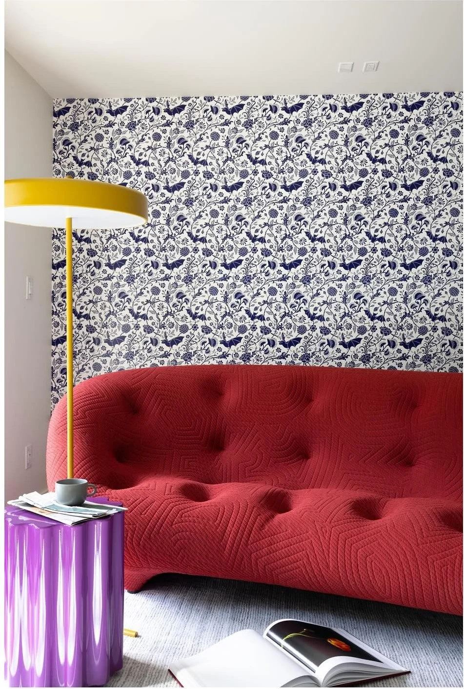 Red tufted sofa beside a purple fluted table and yellow lamp