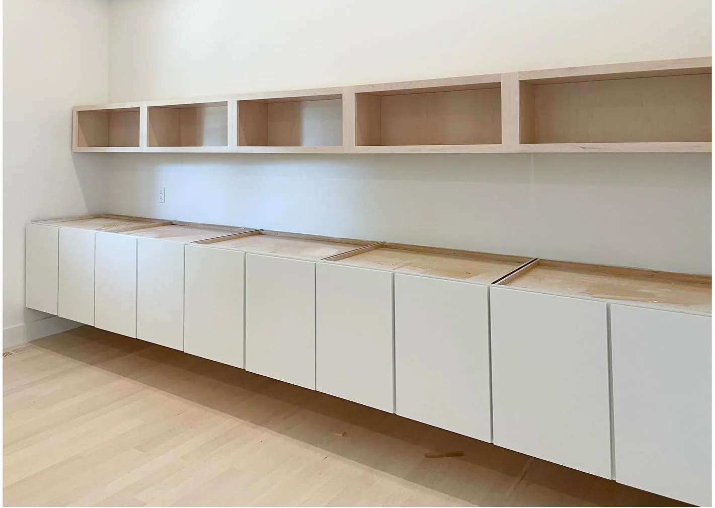 New white lower cabinets and pale wood open shelving during installation