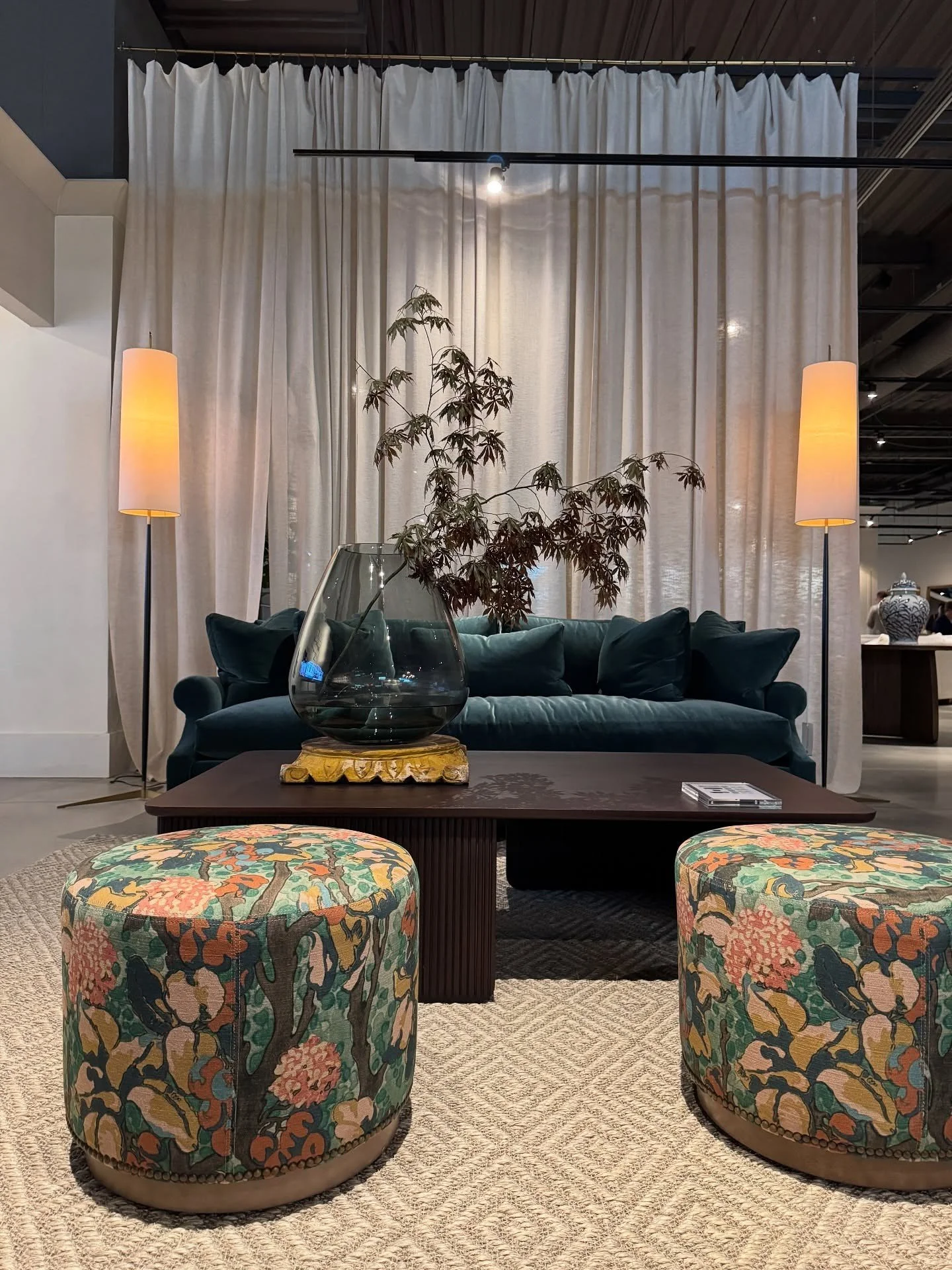 Dark green sofa with floral ottomans in a showroom setting