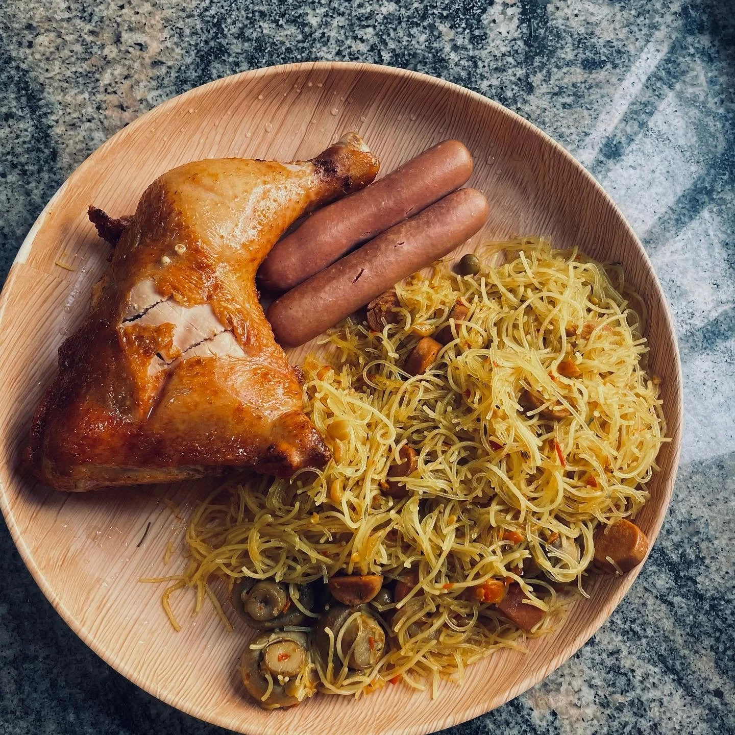 Plate of roasted chicken, sausages, and stir-fried rice noodles with vegetables