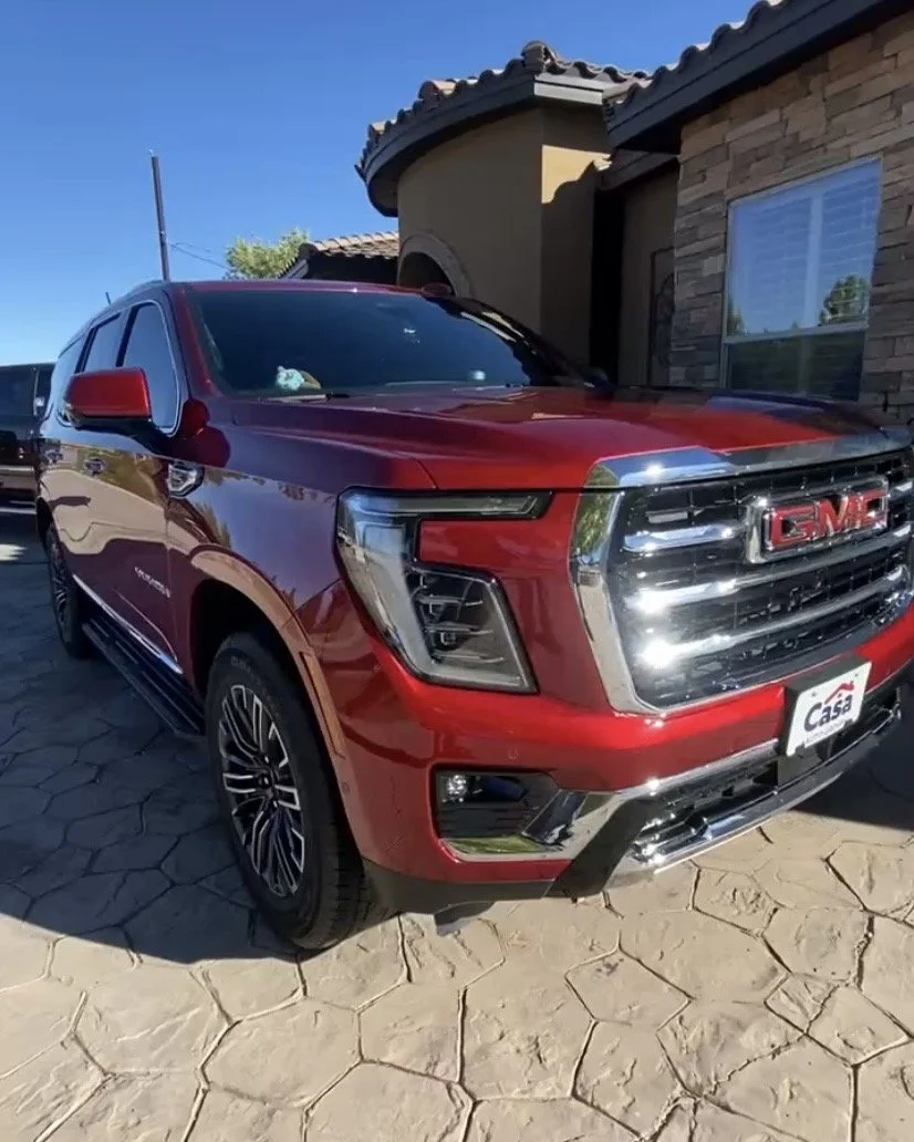 Detailed Red GMC Sierra pickup truck parked in front of a stucco and stone house.