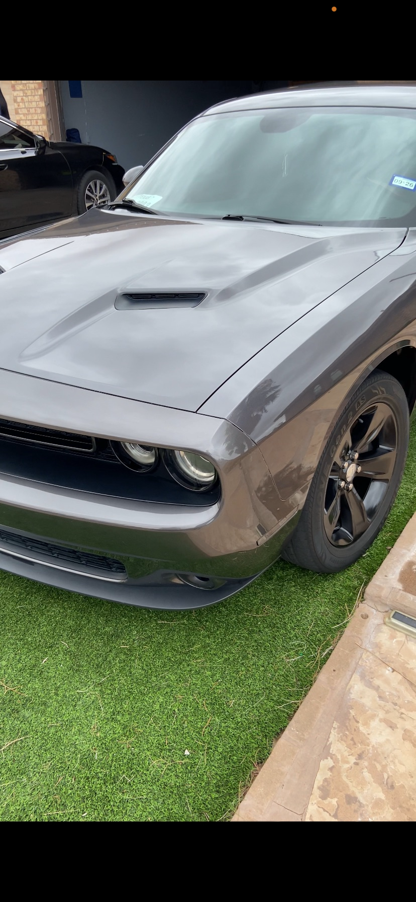Front three-quarter view of a Detailed gray Dodge Challenger parked on grass beside a driveway.