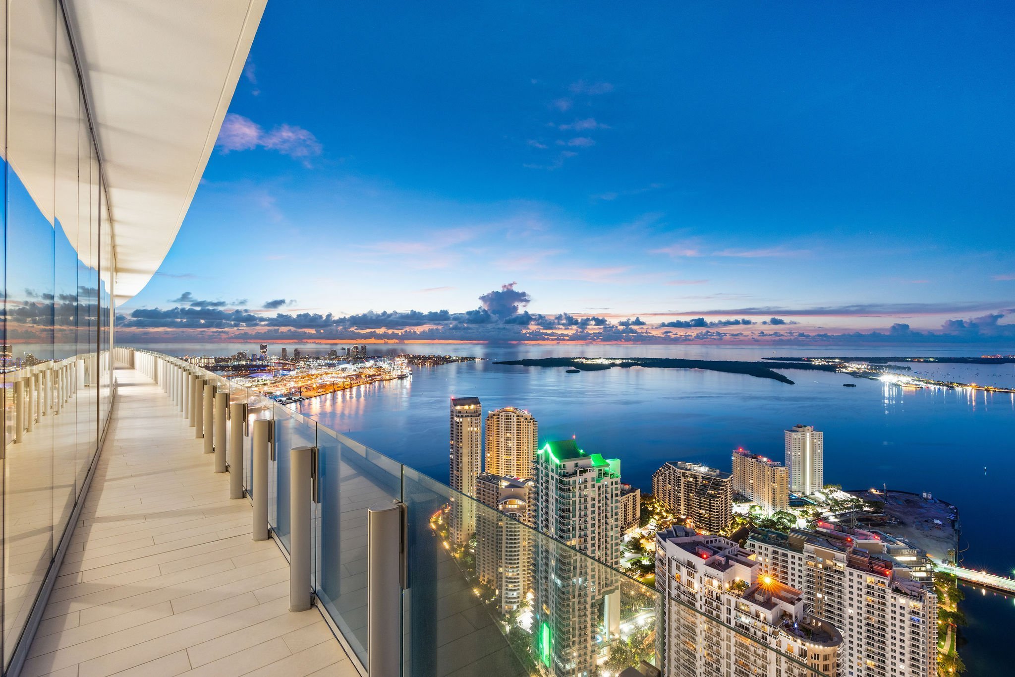 Aston Martin Residences PH6001C curved wraparound terrace and illuminated Biscayne Bay at blue hour, Miami
