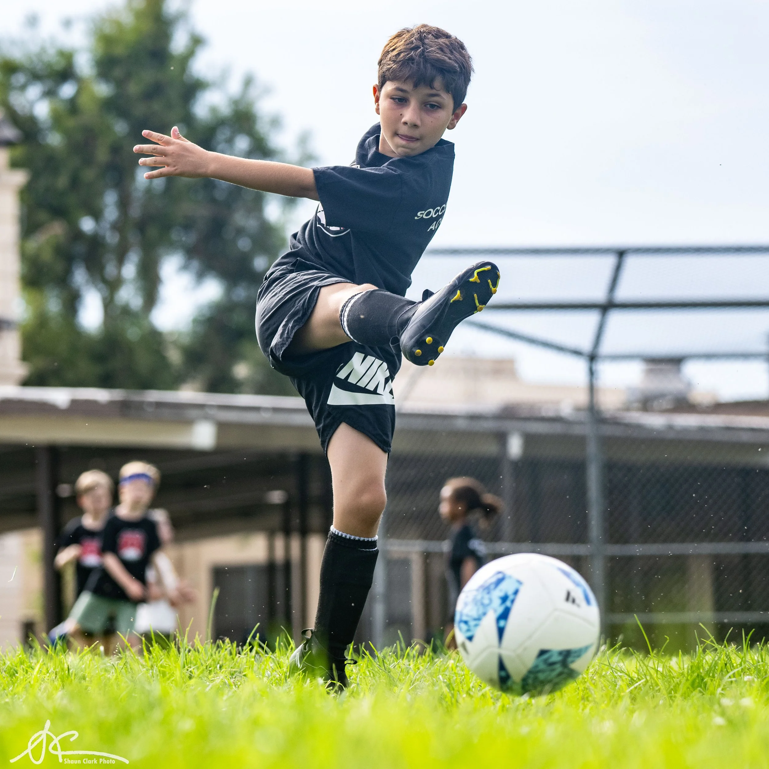 Youth soccer player kicking a ball on a grassy field during a game