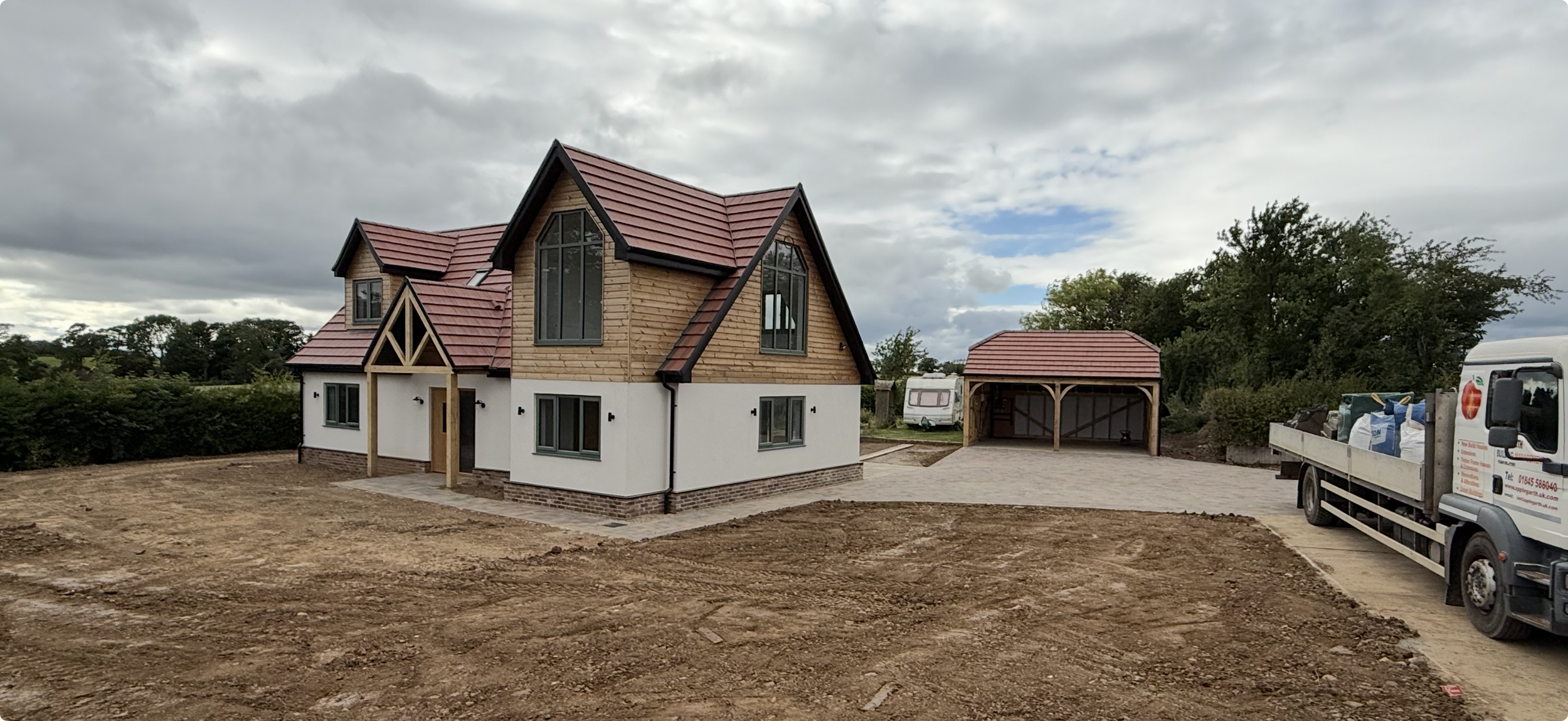 Newly built wood-and-white house with red tiled gable roof, detached garage