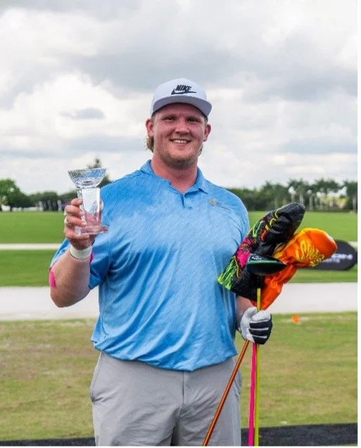 Smiling golfer holding a trophy and colorful golf bag on a golf course