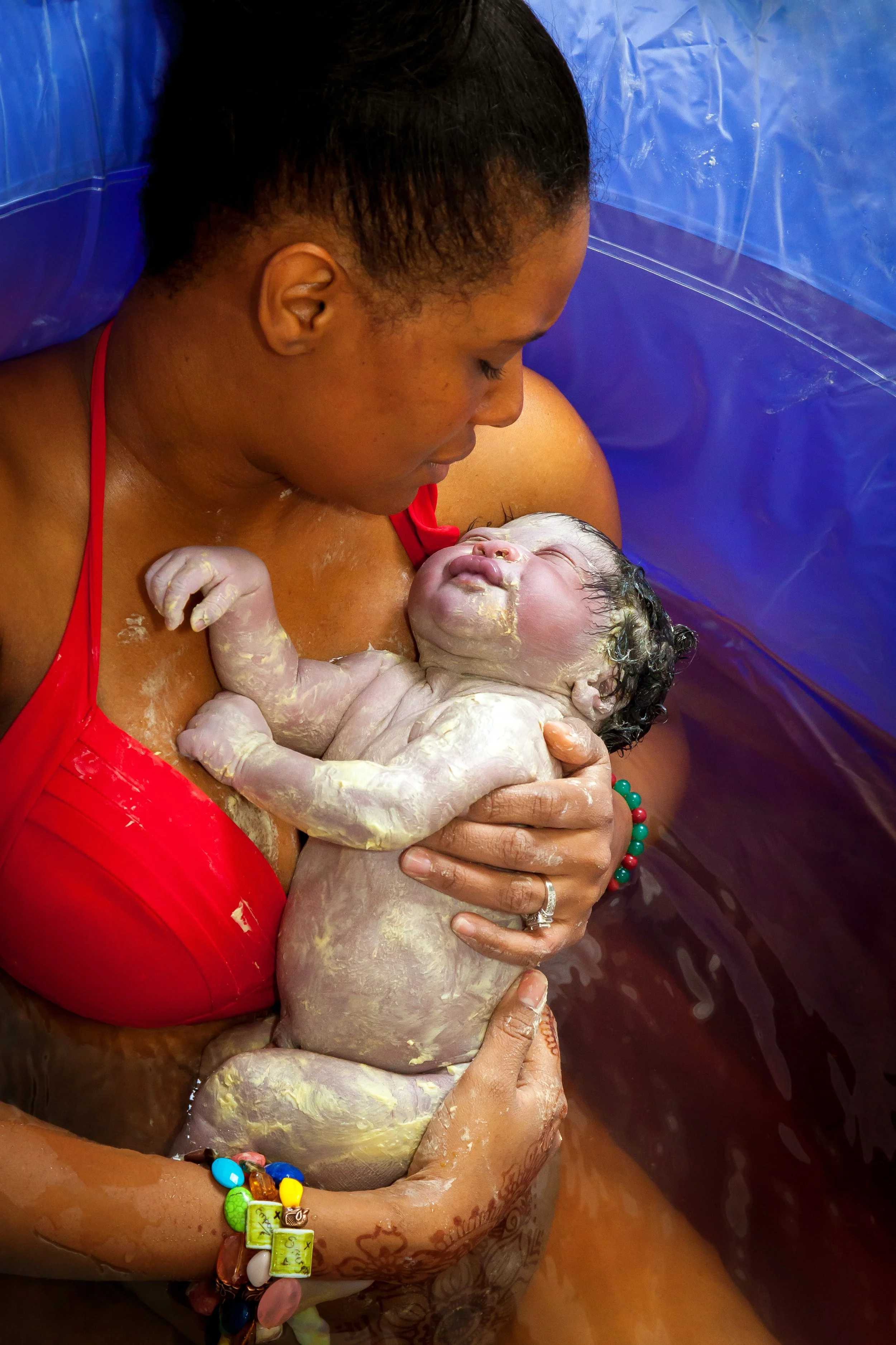 Mother in a birthing pool holding her newborn baby immediately after delivery