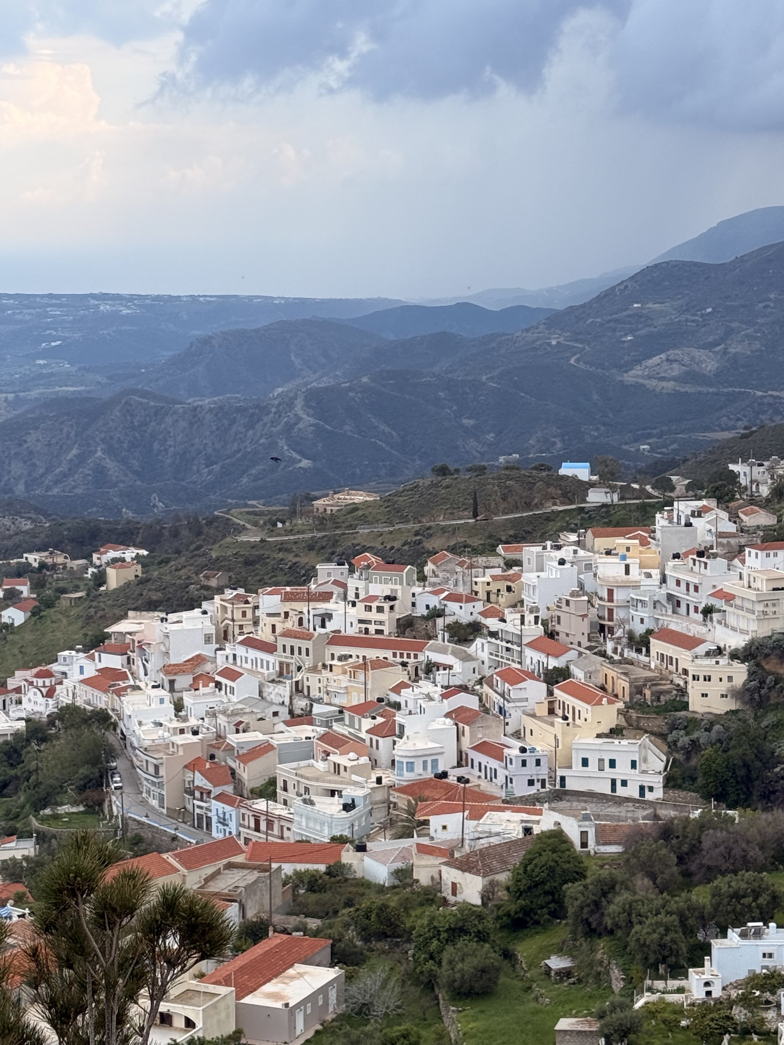 Mountain village with white houses and red tile roofs beneath a cloudy sky