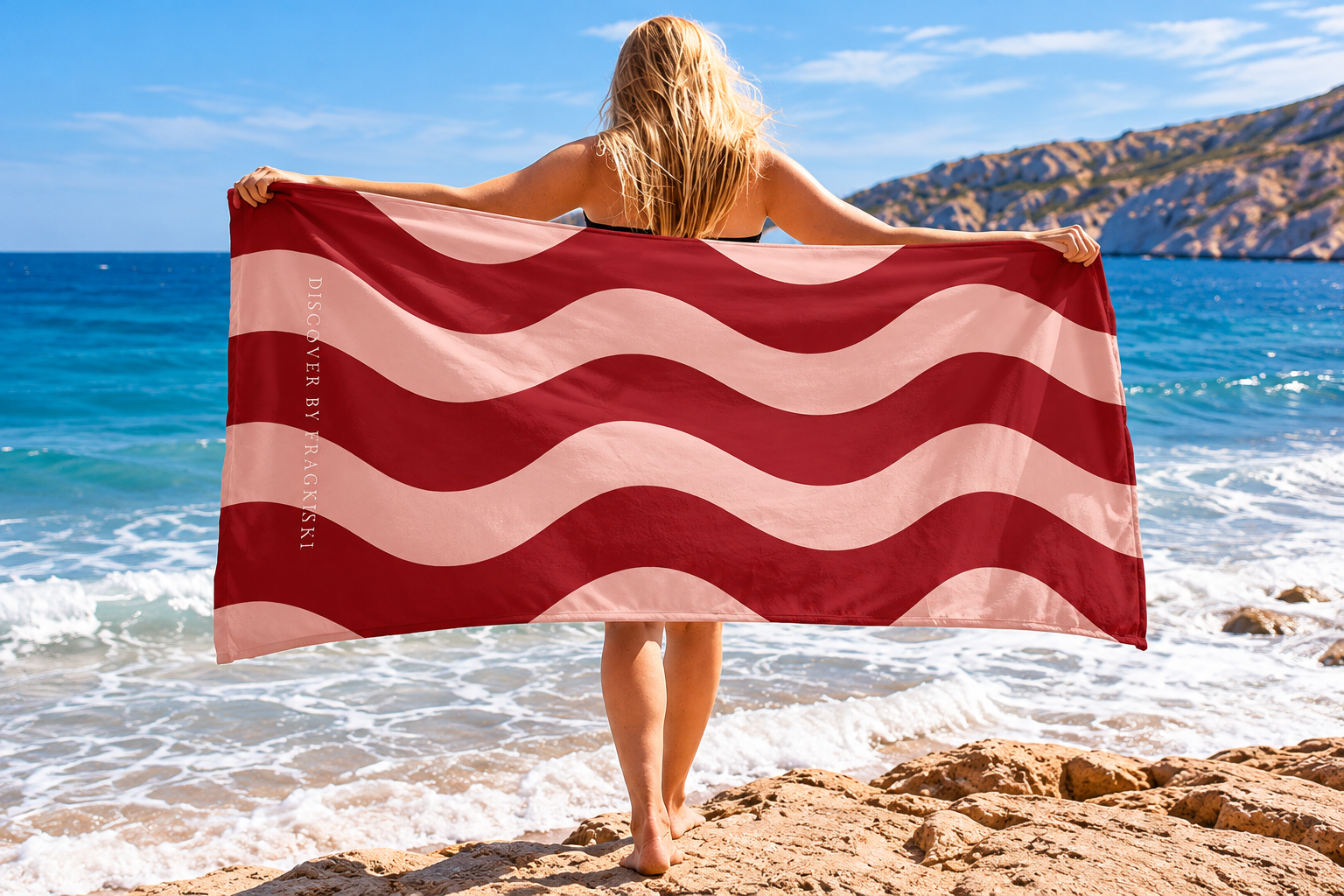Woman holding a red and pink striped beach towel by the Mediterranean Sea