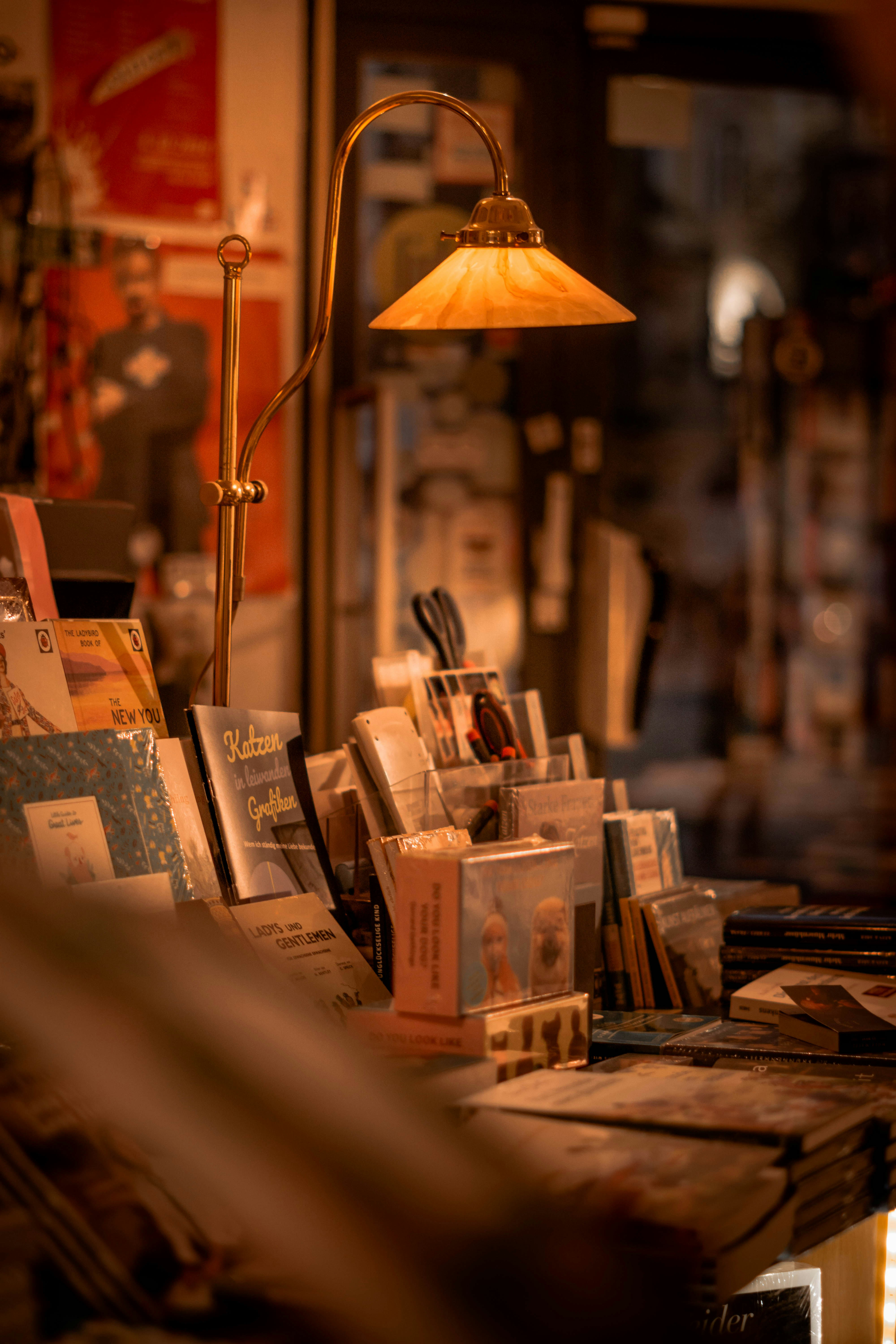 Warmly lit vintage desk lamp illuminating a display of books and stationery in a bookstore