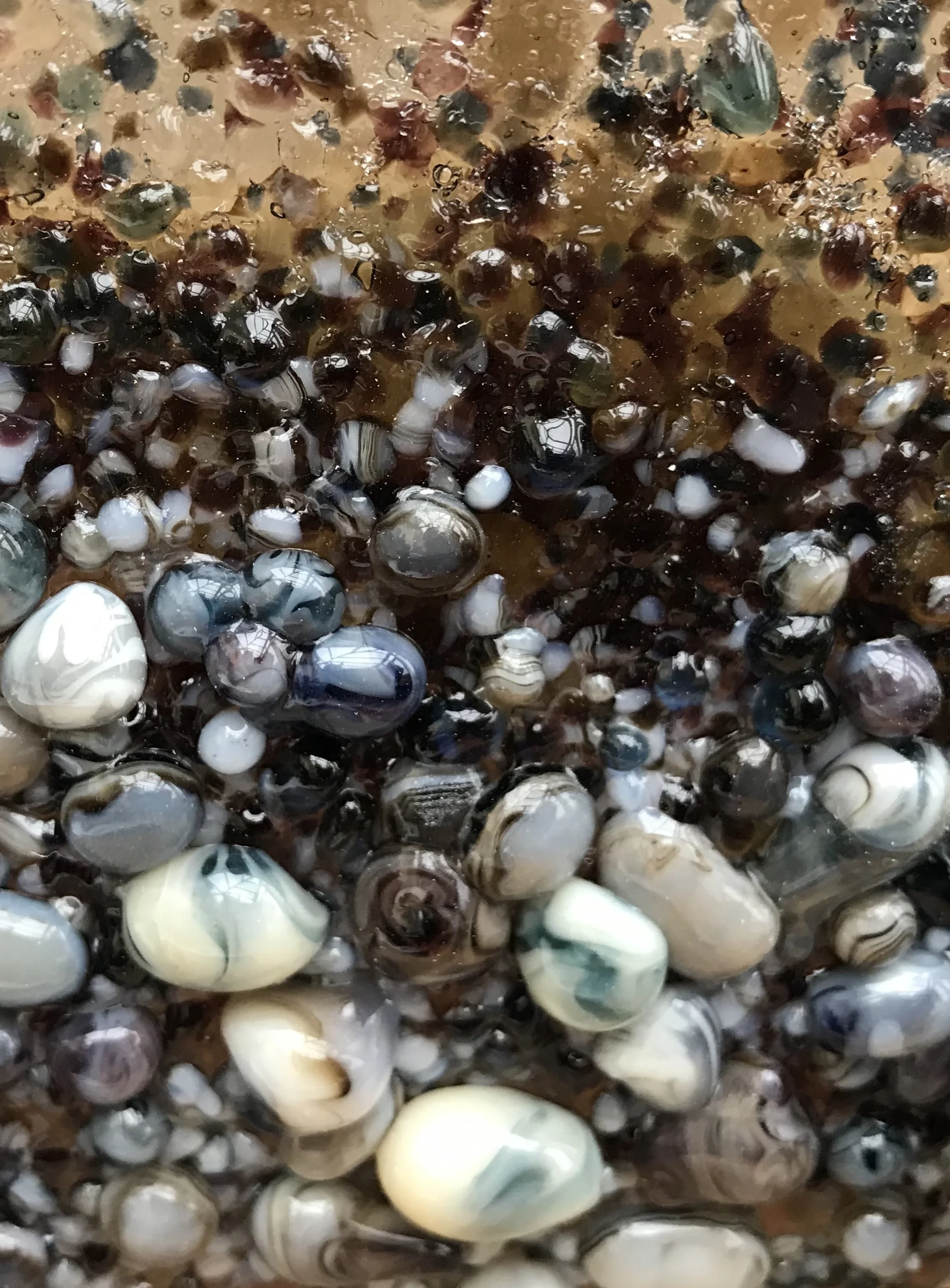 Close-up of assorted colorful polished stones and crystals embedded in translucent amber resin
