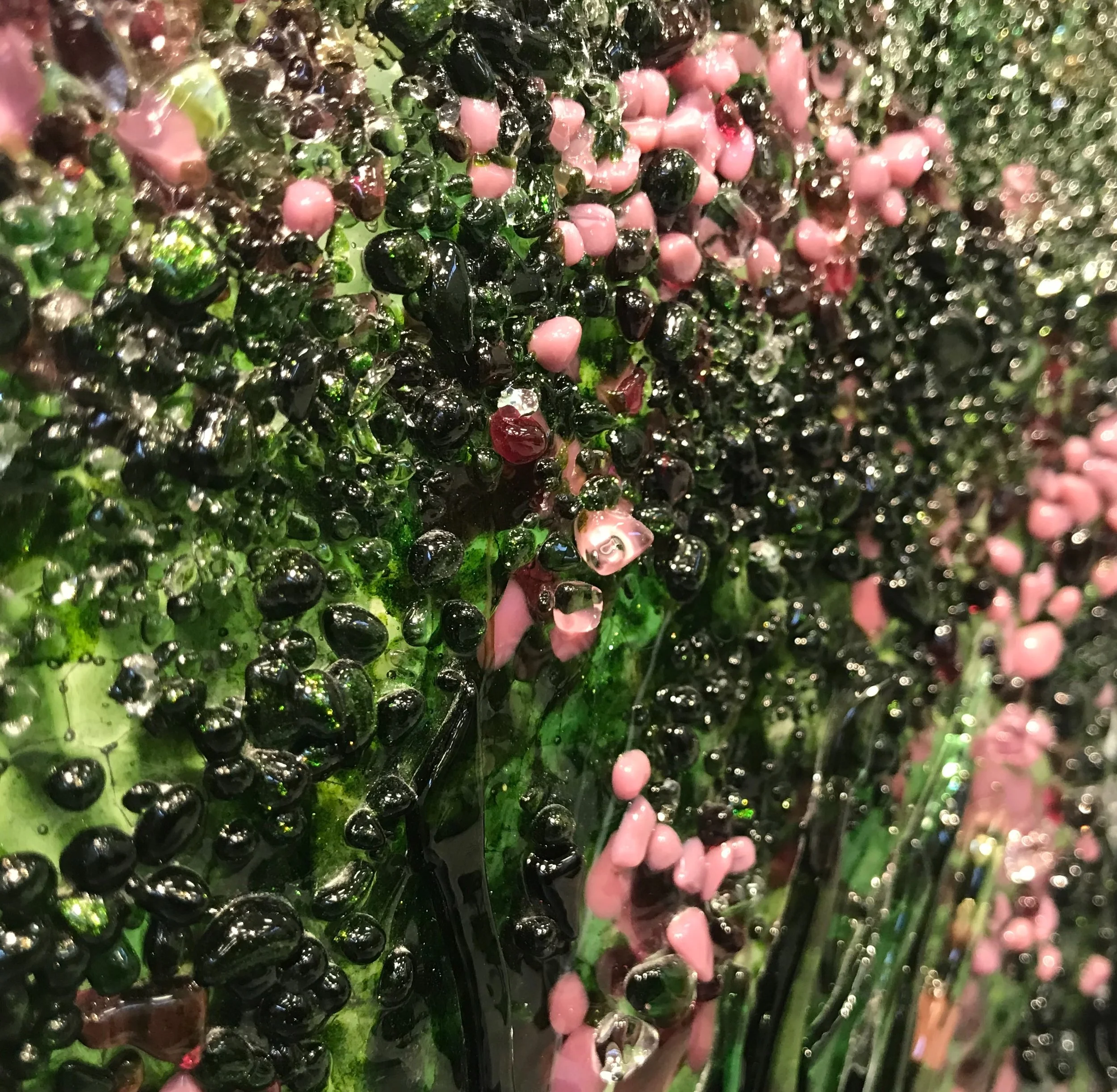 Close-up of glossy black, green, pink, and multicolored polished stones and glass beads