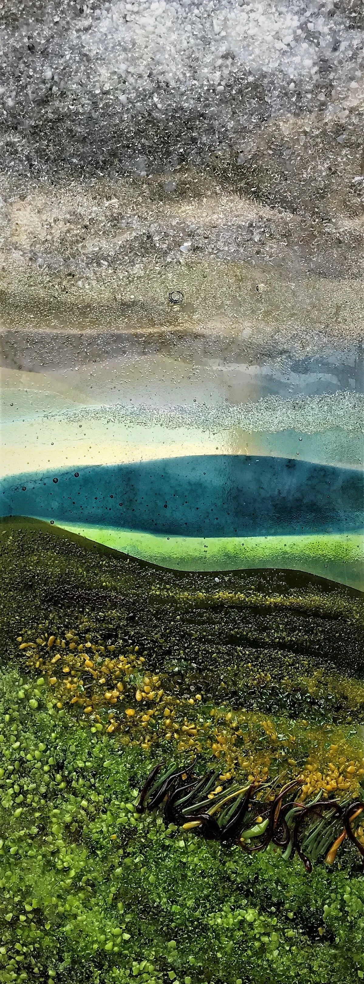 Close-up abstract view of colorful layered sea glass with textured green, blue, yellow, and clear pieces
