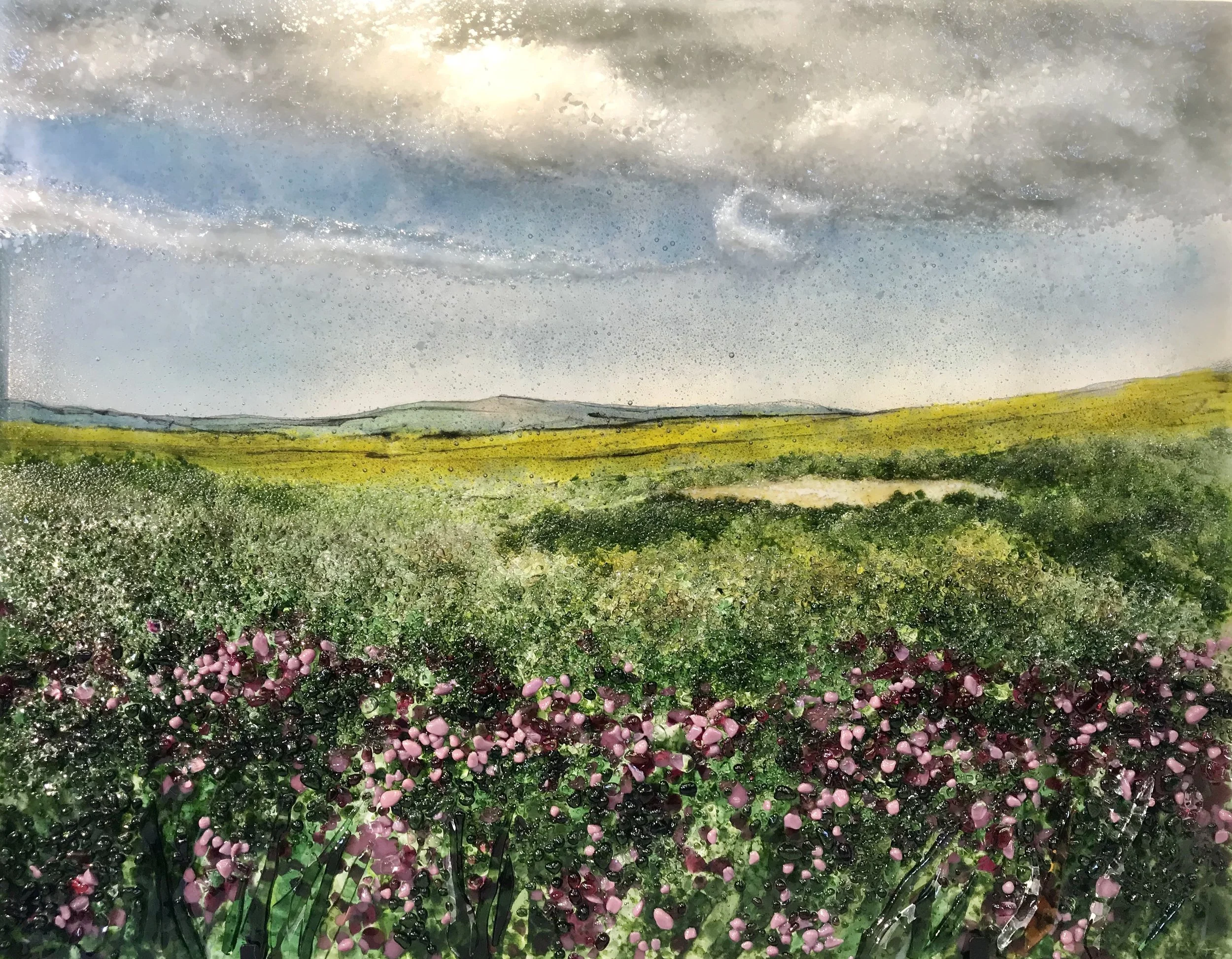 North Yorkshire Moors - glass landscape of green and purple heather beneath a cloudy blue-grey sky.
