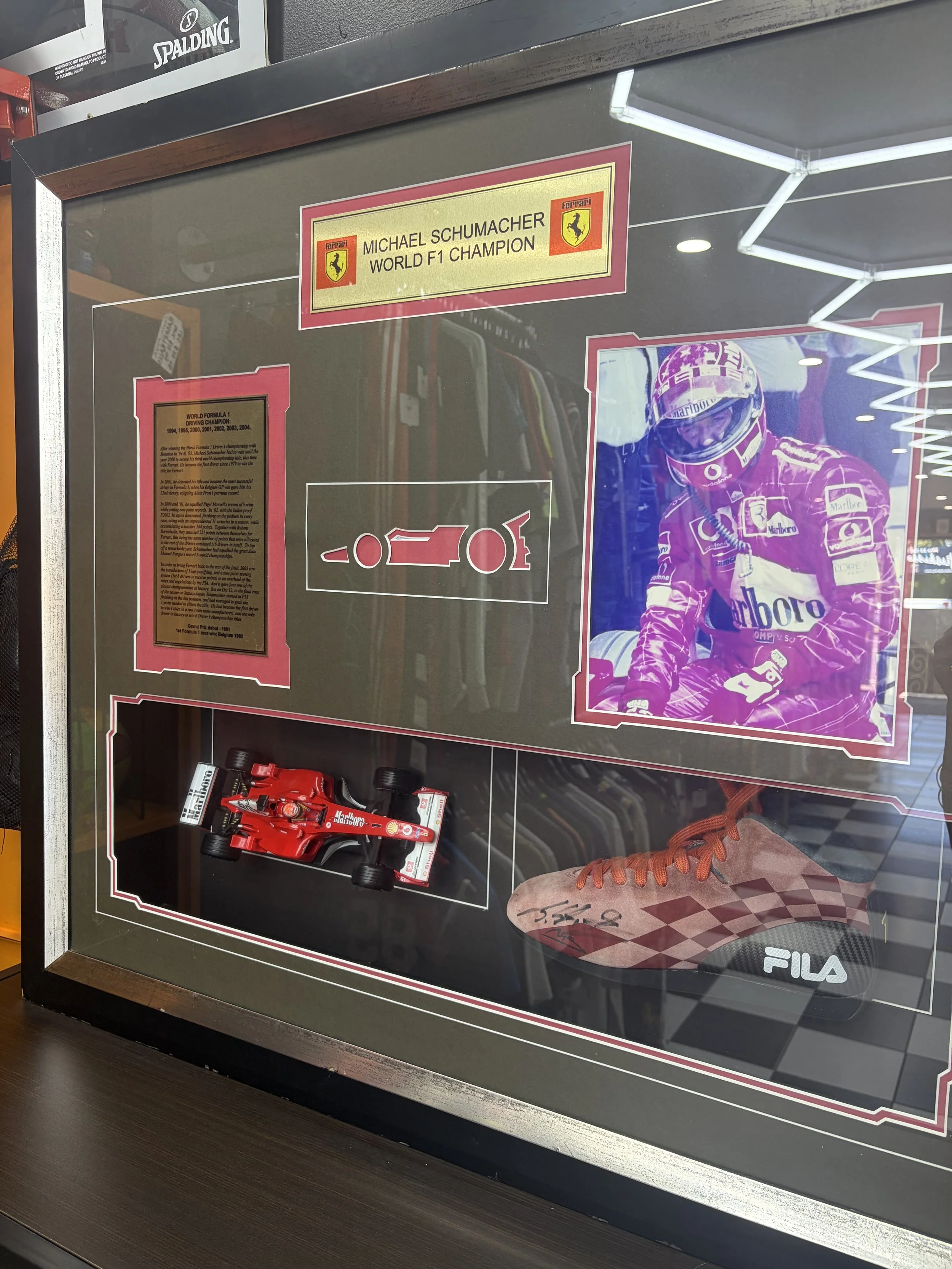 Framed Michael Schumacher Ferrari Formula One memorabilia display featuring a signed racing shoe, Ferrari model car, and photograph.