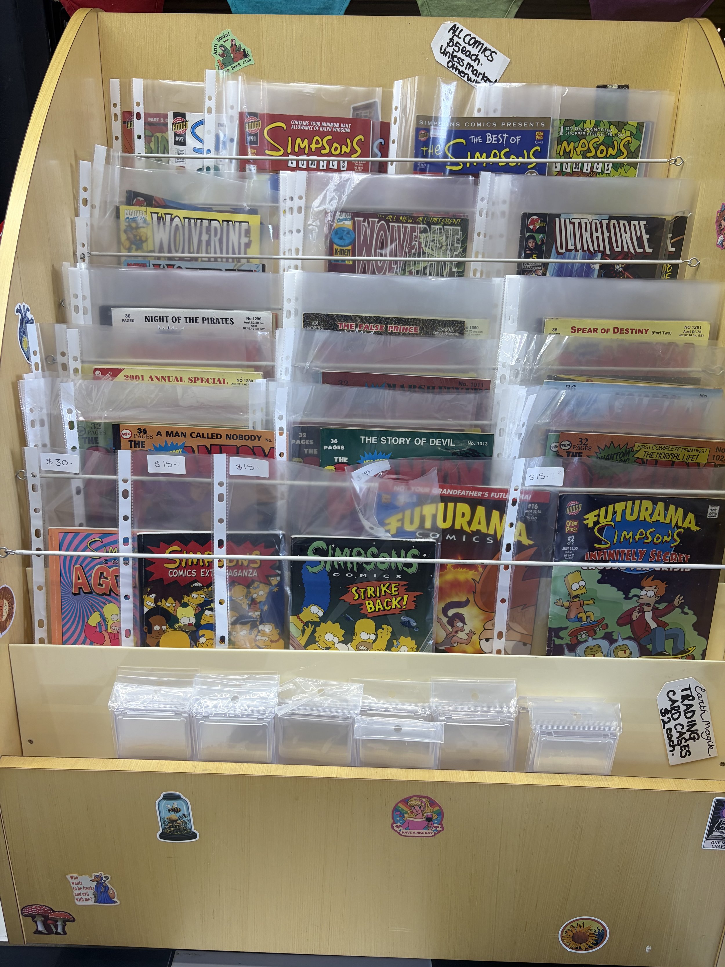 Display rack of bagged vintage comic books, including The Simpsons, Wolverine, Ultraverse, Futurama, and other comics.