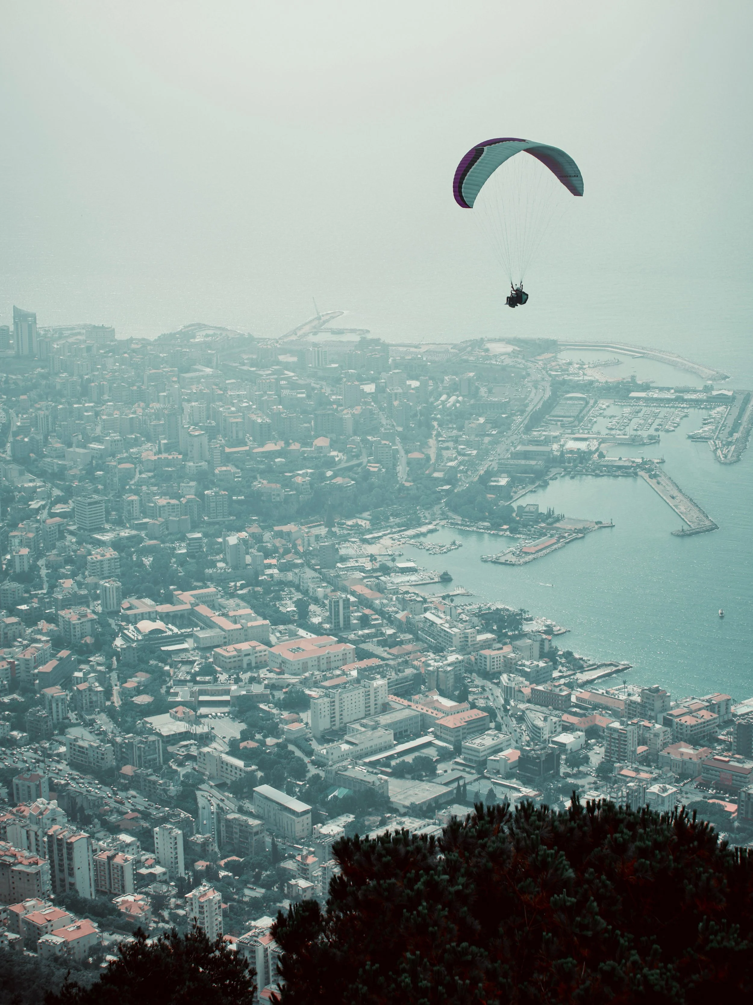 Paraglider flying over a dense coastal city and marina in Beirut, Lebanon. Photo by David Ferry Jr.