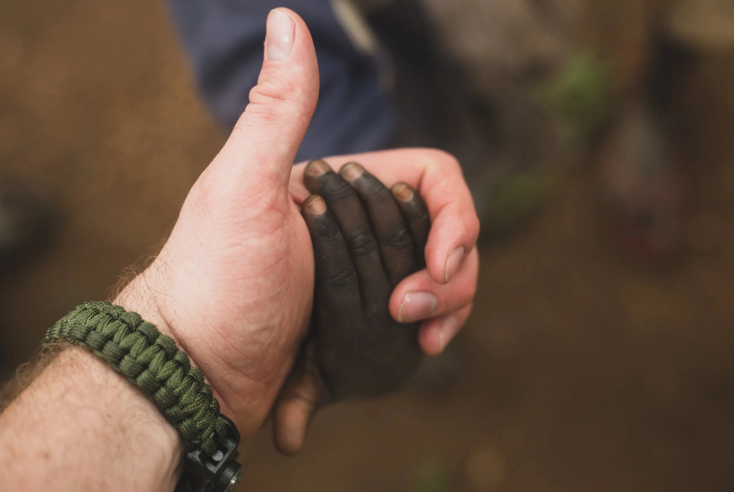 Close-up of a person holding a Sudanese refugee's hand with an upright thumb. Photo by David Ferry Jr.