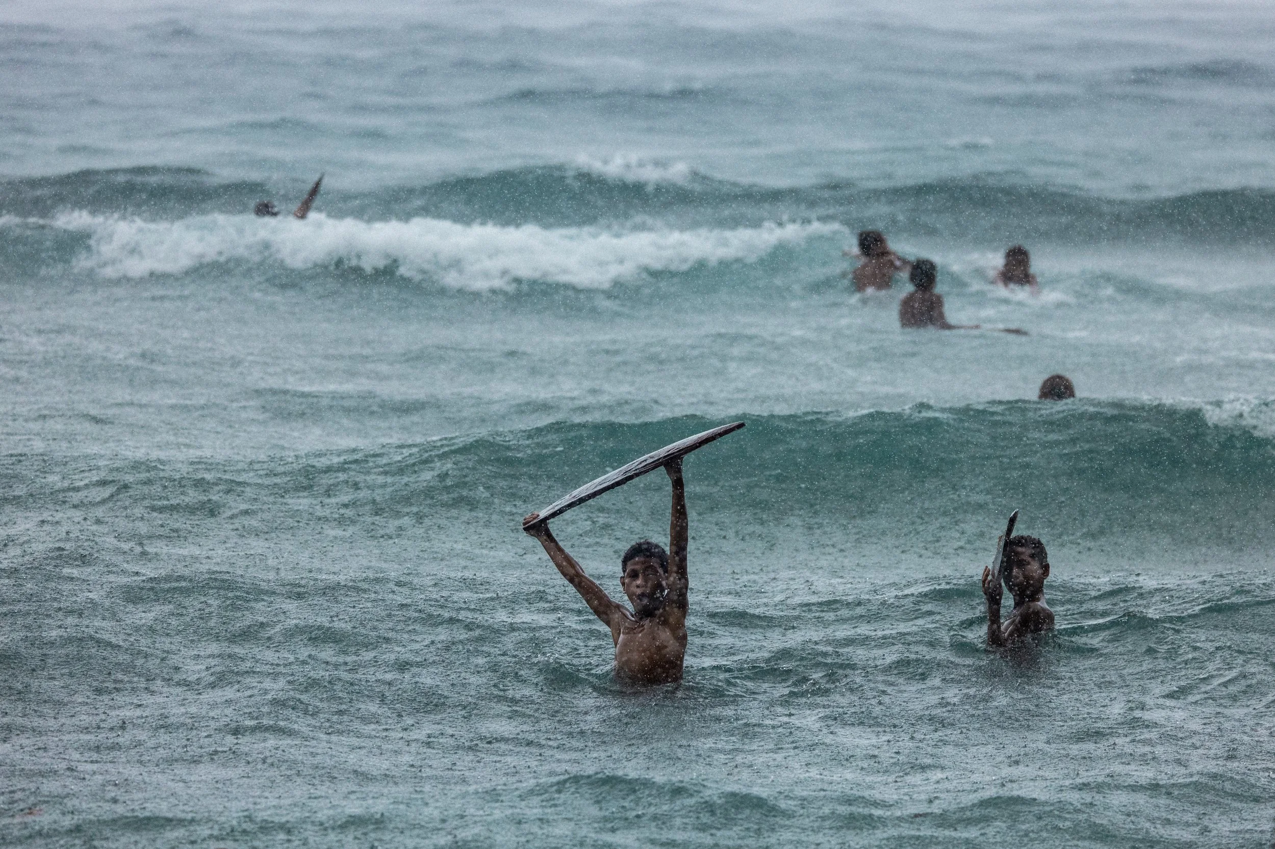 Remote Papua New Guinea surfers riding waves in the ocean during a rainy day. Photo by David Ferry Jr.