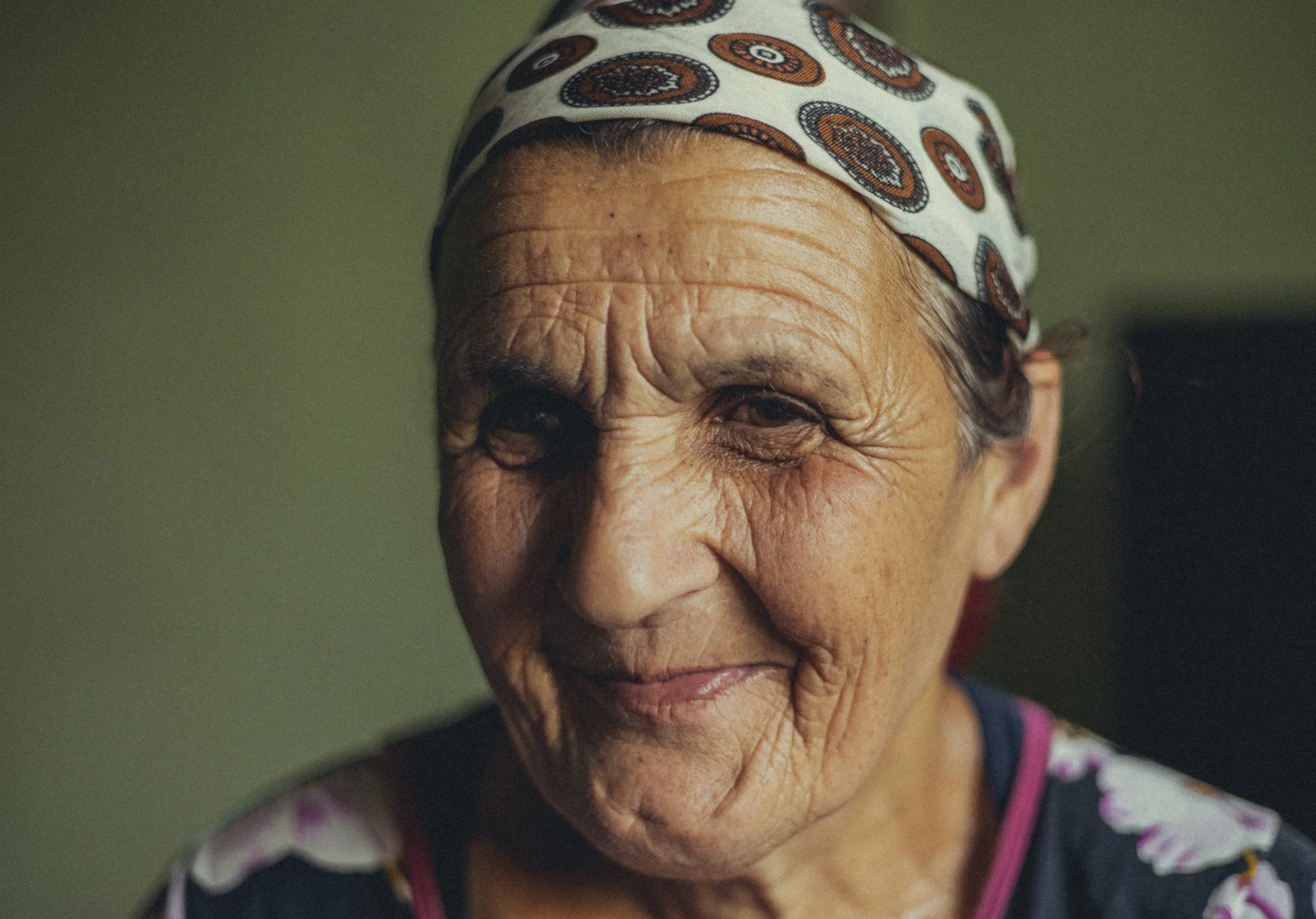 Close-up portrait of an elderly woman wearing a patterned headscarf and smiling gently in Azerbaijan. Photo by David Ferry Jr.
