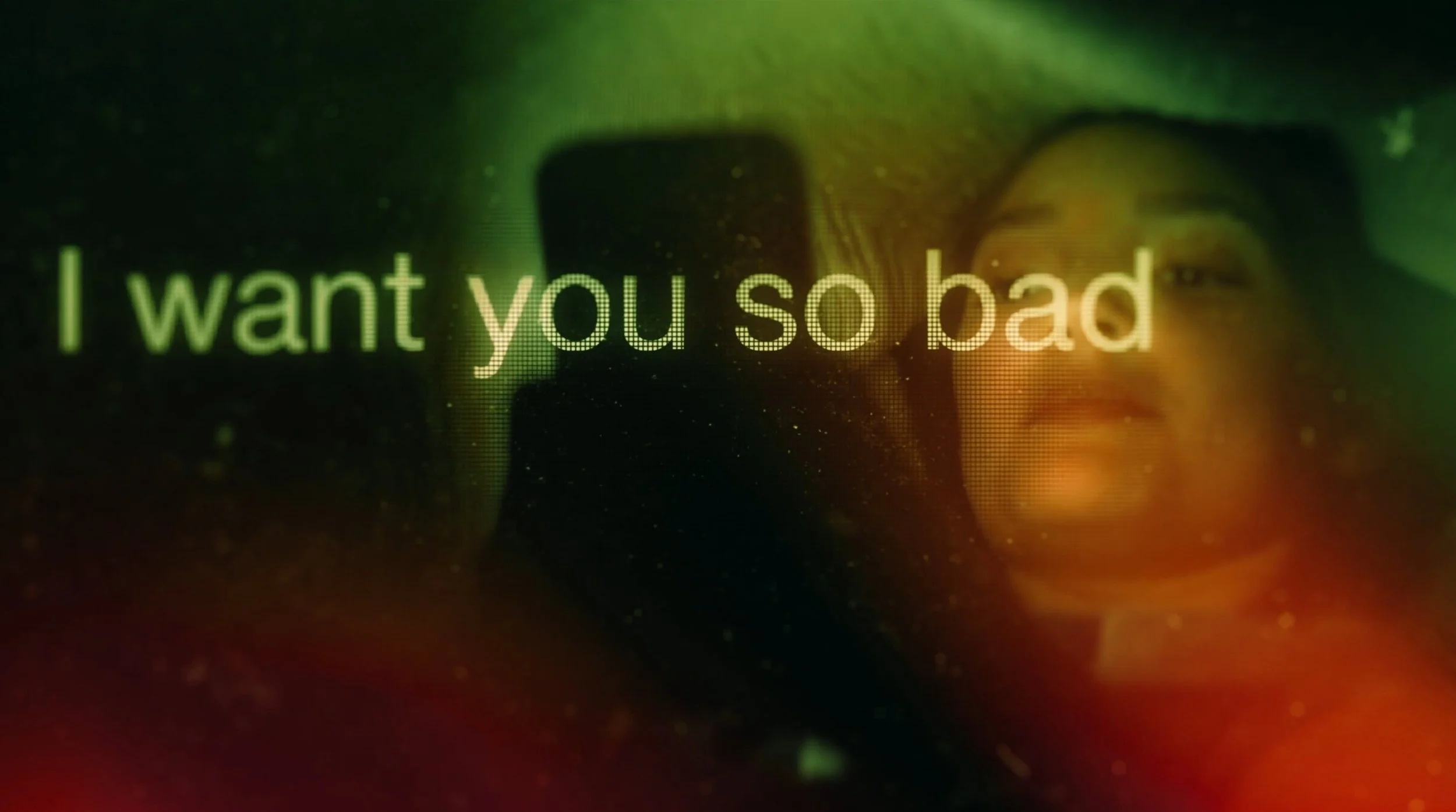 Glowing text reading “I want you so bad” over a blurred close-up of a person wearing glasses