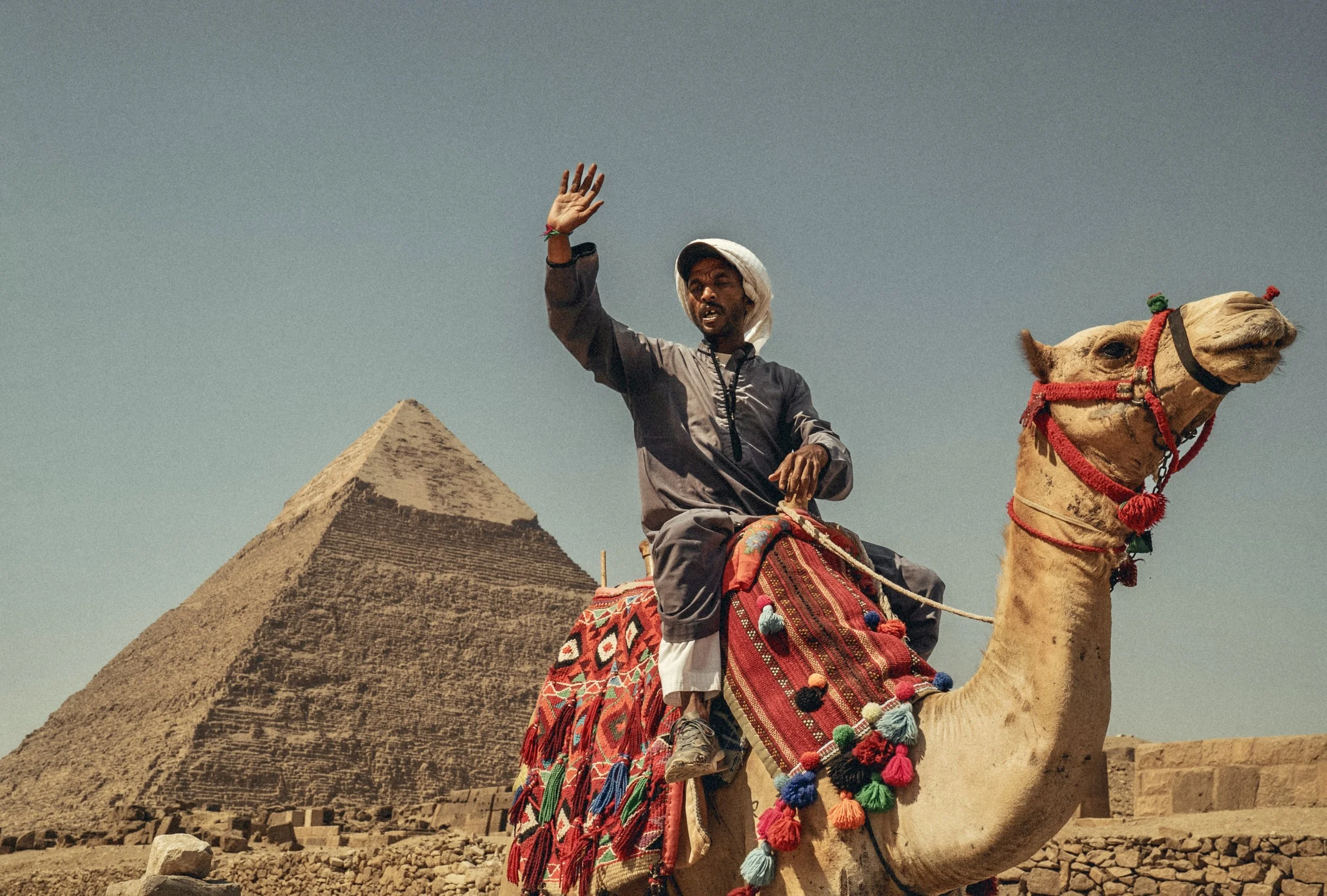 Camel rider waving in front of the Pyramids of Giza in Egypt. Photo by David Ferry Jr.