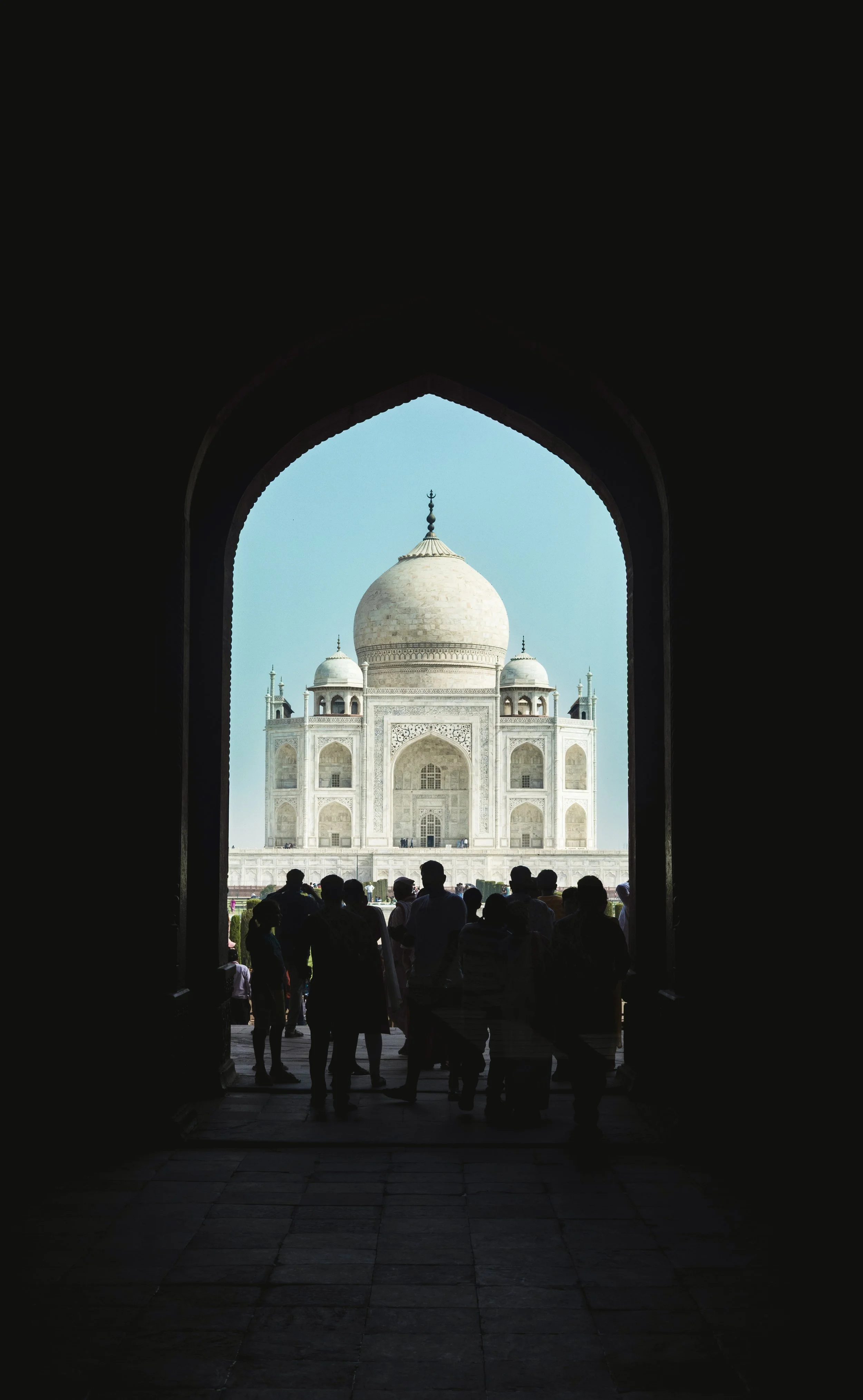 The Taj Mahal framed by a dark archway, with silhouetted visitors in the foreground. Photo by David Ferry Jr.