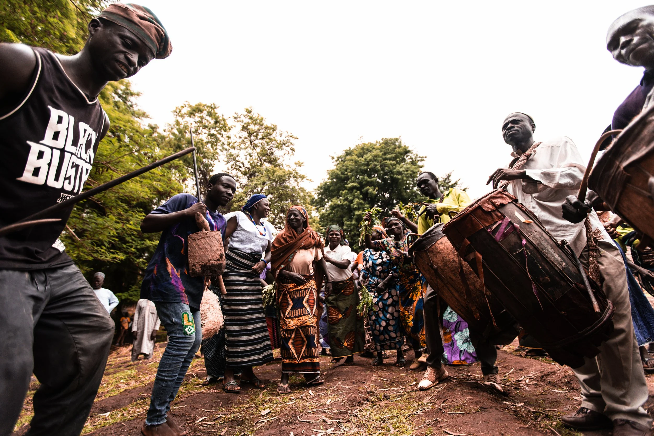 Group of Nigerian people in colorful clothing dancing and playing large traditional drums outdoors. Photo by David Ferry Jr.