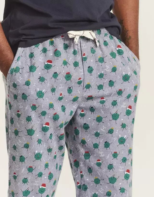 Gray pajama pants with a festive green cartoon monster pattern and Santa hats. Hand painted surface print designs. Freelance print designer.