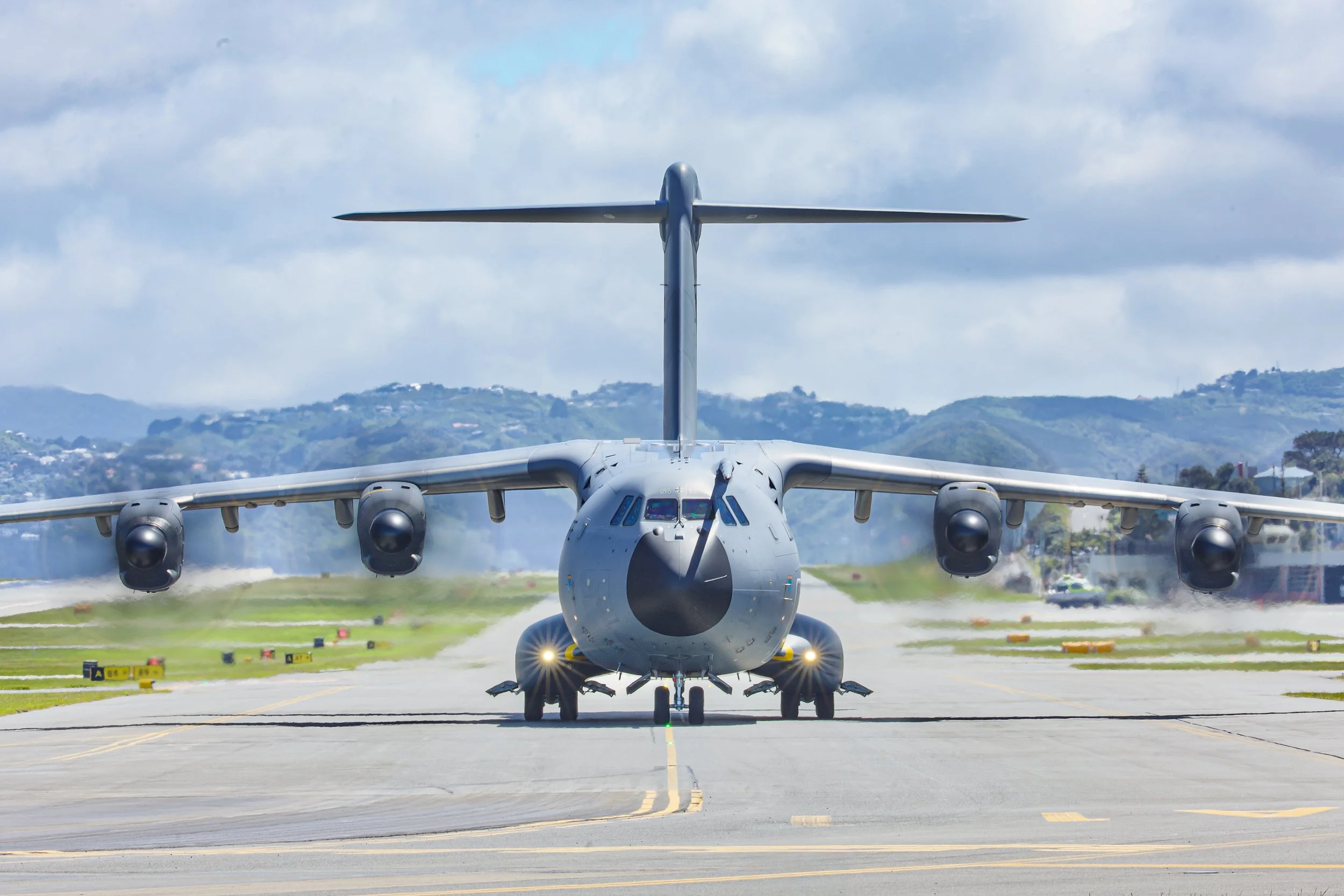 Military transport aircraft with four turboprop engines taxiing on an airport runway