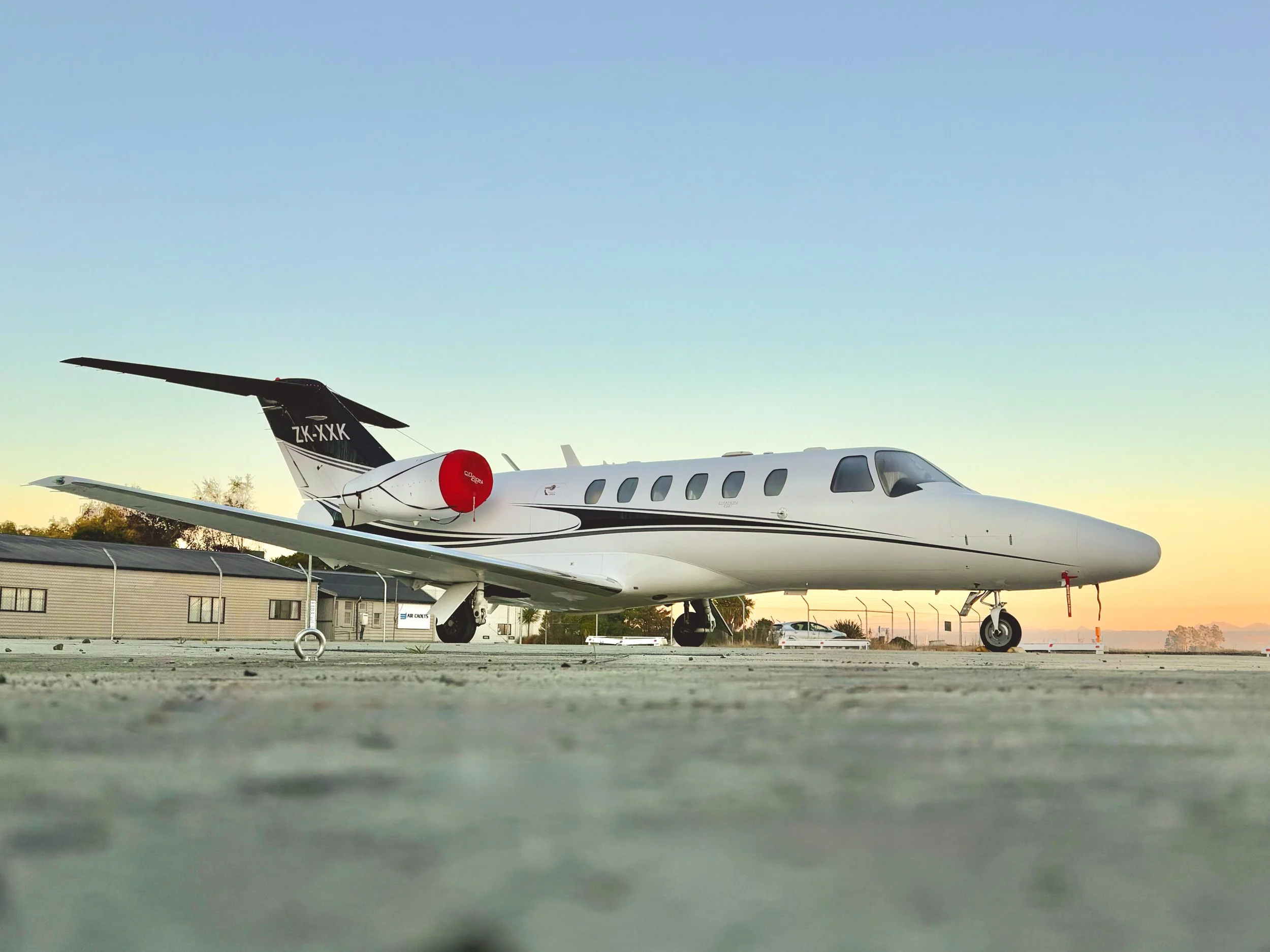 White private jet parked on an airport runway at sunset