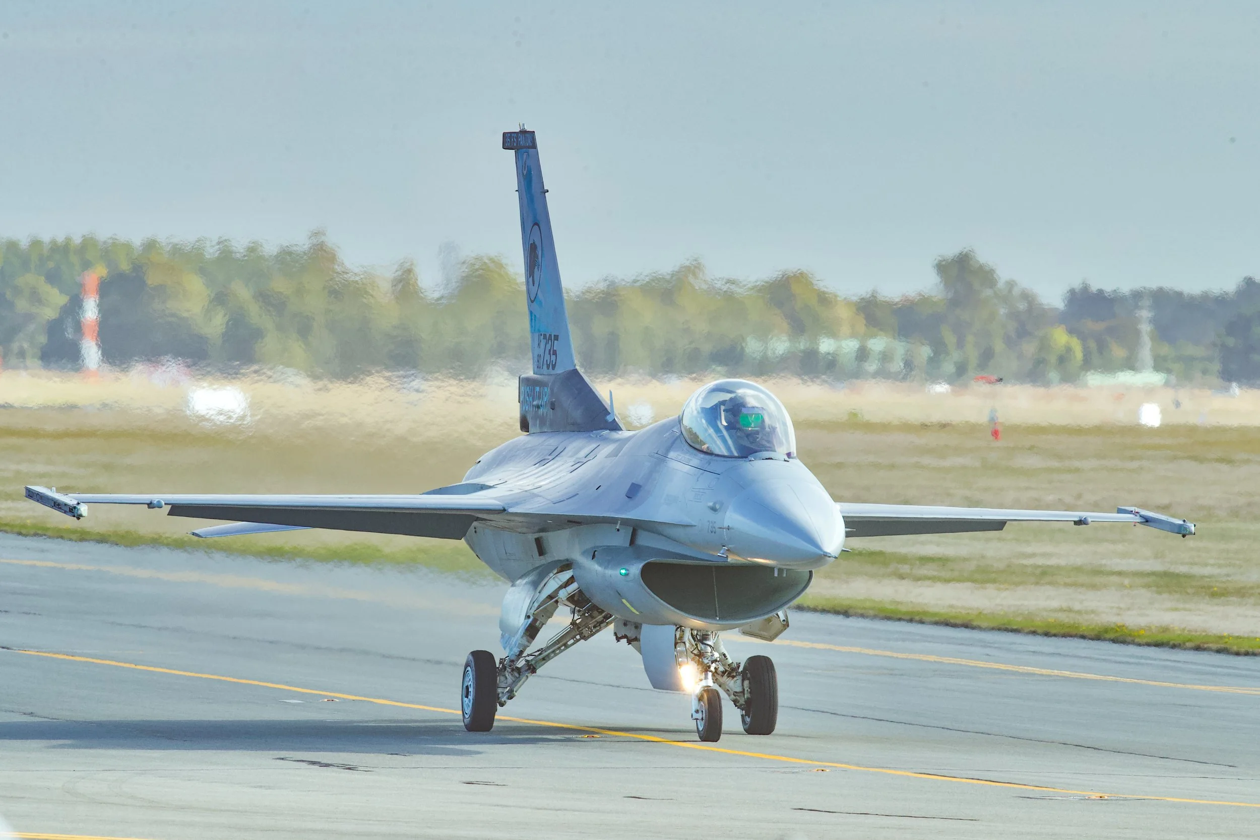 F-16 fighter jet taxiing on a runway with landing gear down