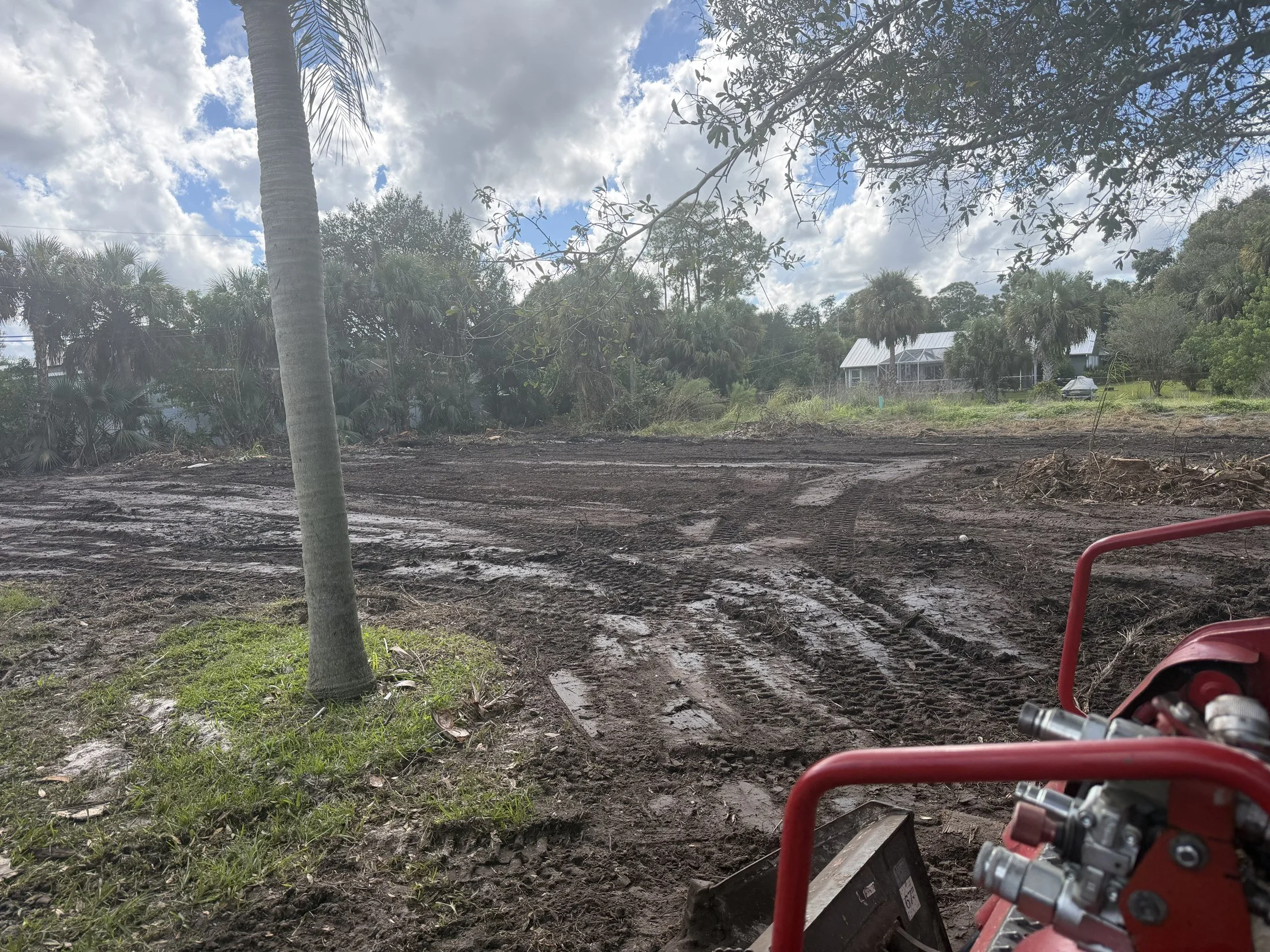 Cleared work area with graded soil and equipment tracks.